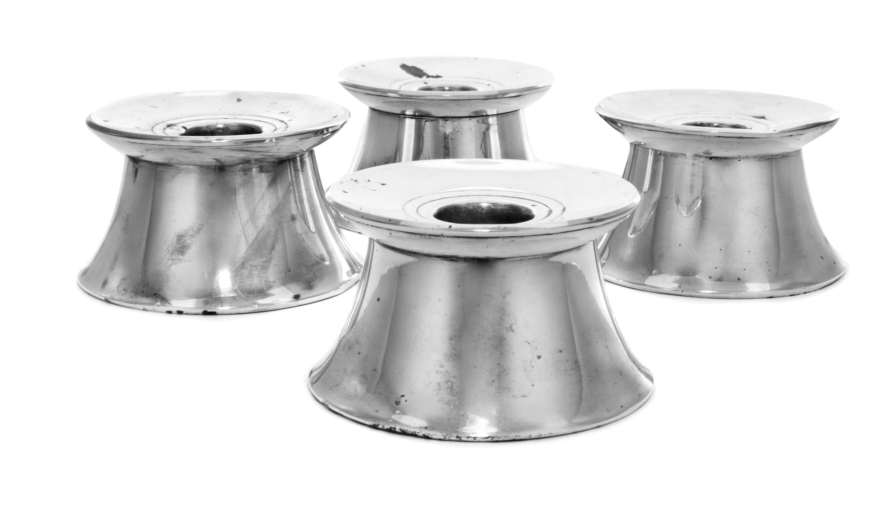 A Set of Four French Silver Candlesticks, Cartier, having a circular rim over a flared base, weighted.