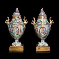 A Pair of Chinese Export Canton Famille Rose Porcelain Covered Urns, Early 19th Century — 清晚期 外銷廣彩人物故事圖獎杯形賞瓶一對