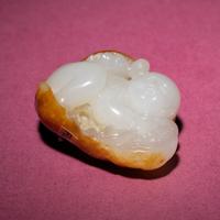 A Chinese Russet and White Jade Carving of a Boy with Lotus Pad, 18th/19th Century — 清中期 白玉留皮童子持荷把件