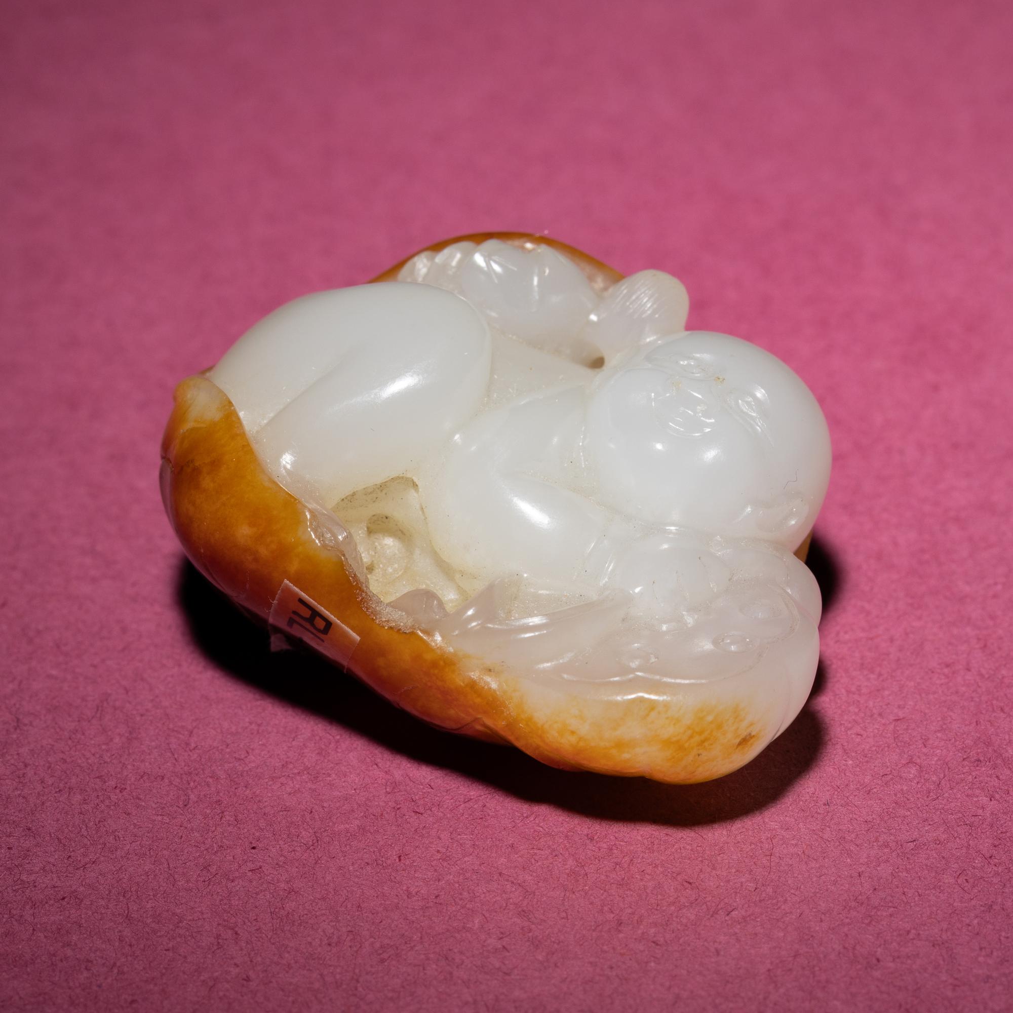 A Chinese Russet and White Jade Carving of a Boy with Lotus Pad, 18th/19th Century — 清中期 白玉留皮童子持荷把件