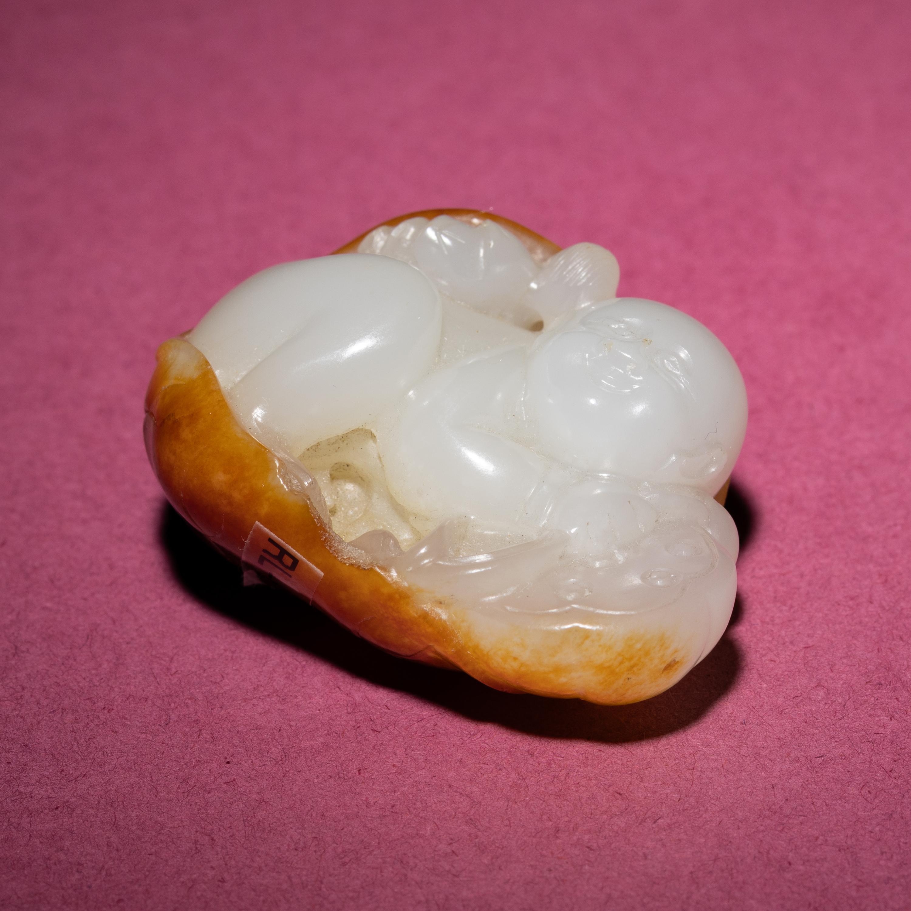 A Chinese Russet and White Jade Carving of a Boy with Lotus Pad, 18th/19th Century — 清中期 白玉留皮童子持荷把件