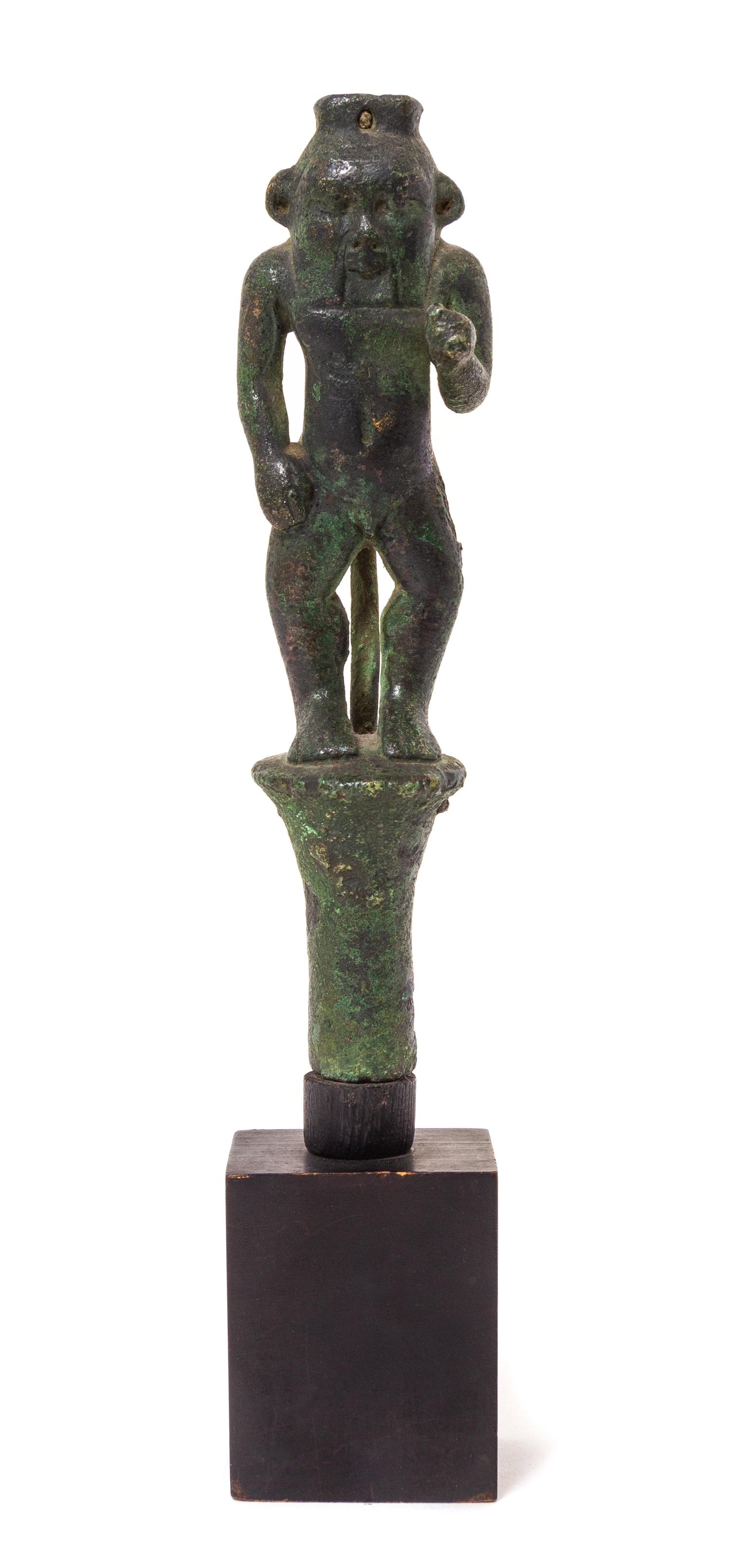 An Egyptian Bronze Bes Standing on a Papyrus Umbel Height 7 inches. — THIRD INTERMEDIATE PERIOD, DYNASTY 21-22, 1070-712 B.C.E.