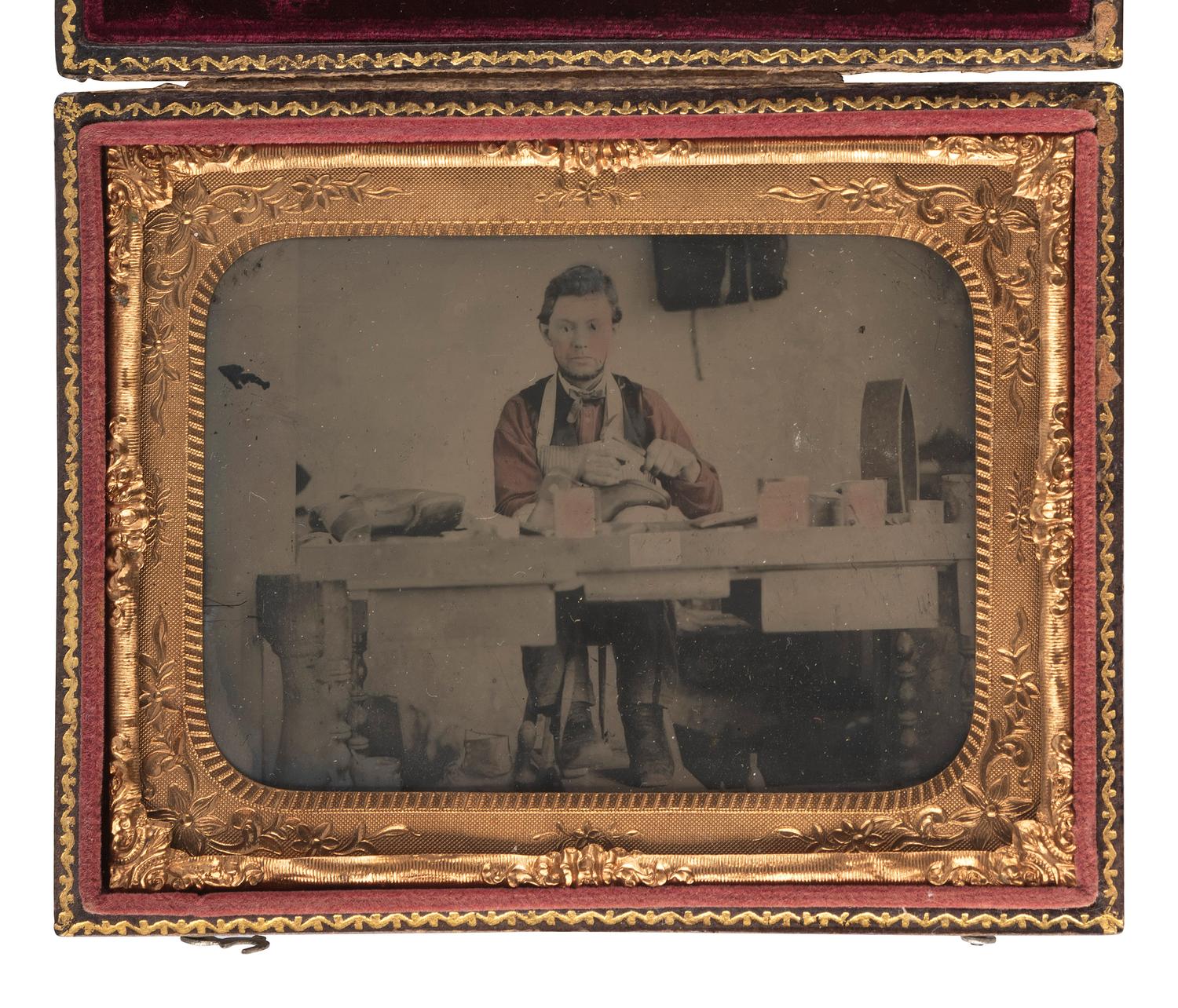 [EARLY PHOTOGRAPHY]. Hand-colored quarter plate ambrotype of a cobbler at work in his shop. [New York]: [Bogardus], n.d.