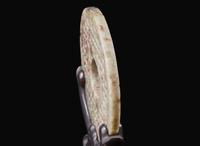 A Chinese archaistic carved mottled grey and russet jade bi disc 玉璧一件