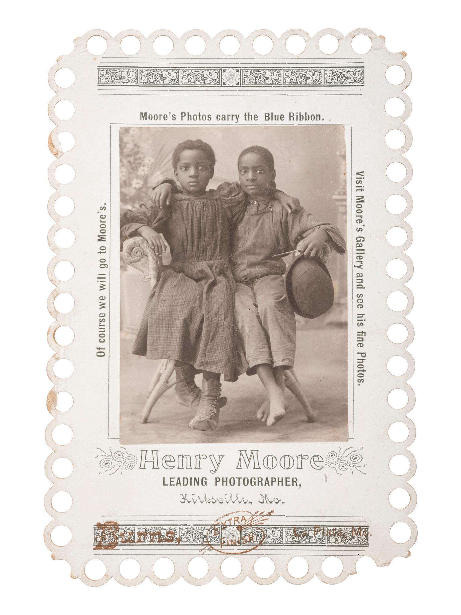 [EARLY PHOTOGRAPHY]. Advertising card for Henry Moore, Kirksville, MO, featuring two young African American subjects posed affectionately. La Plata, MO: Burns, ca 1900.