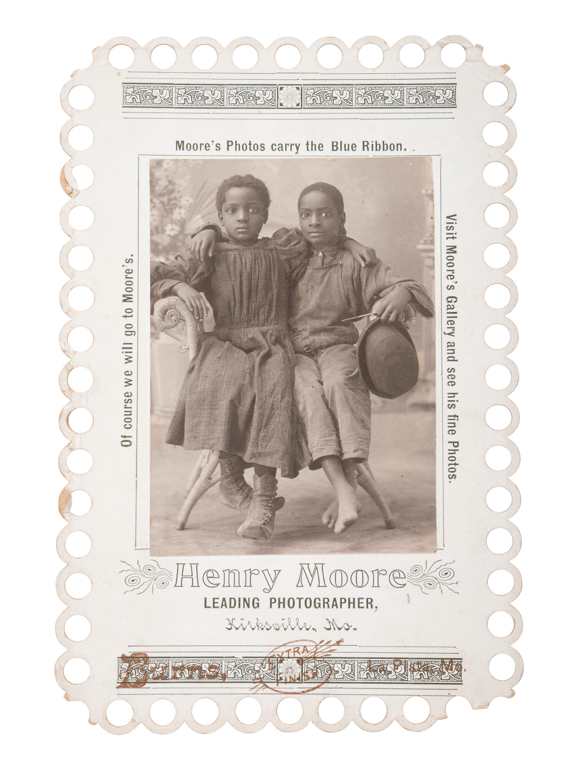 [EARLY PHOTOGRAPHY]. Advertising card for Henry Moore, Kirksville, MO, featuring two young African American subjects posed affectionately. La Plata, MO: Burns, ca 1900.