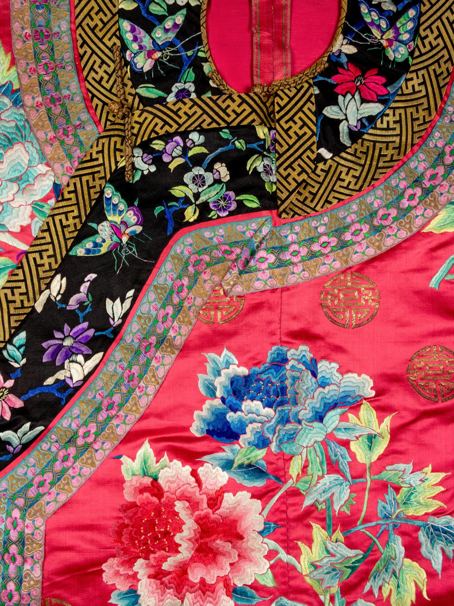 A Chinese Red Ground Embroidered Silk Manchu Lady's Informal Robe, Changyi, Late 19th Century 清晚期 桃紅緞綉牡丹團壽紋氅衣
