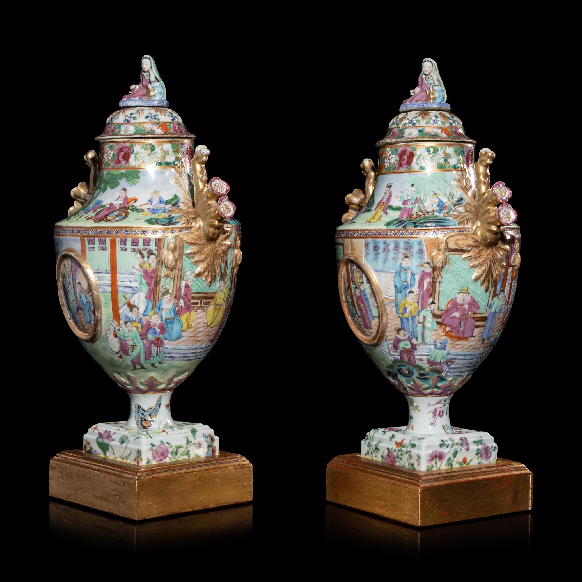 A Pair of Chinese Export Canton Famille Rose Porcelain Covered Urns, Early 19th Century — 清晚期 外銷廣彩人物故事圖獎杯形賞瓶一對
