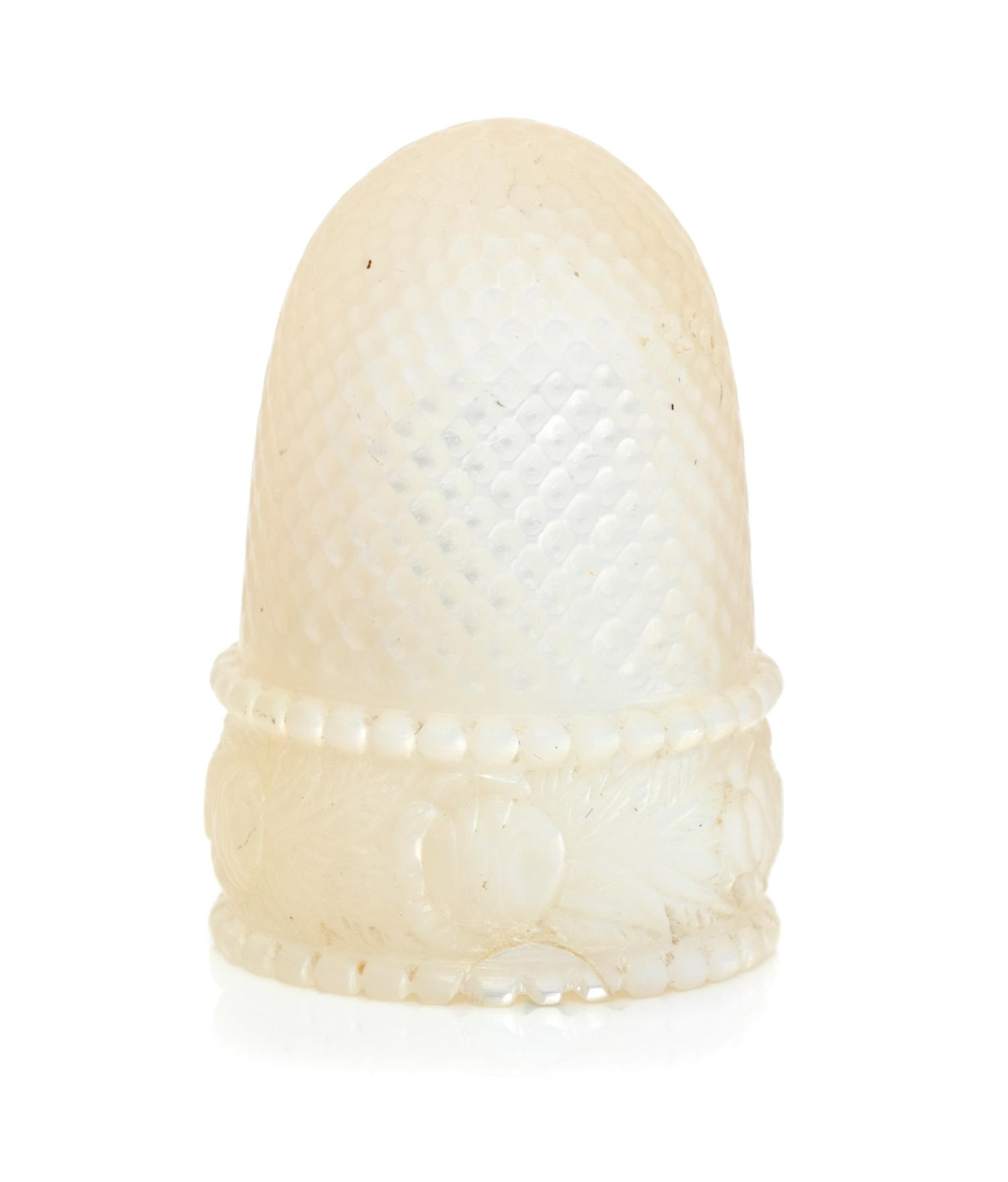 A French Palais Royal Mother-of-Pearl Thimble, 19th Century, the domed body above the band carved to show floral and foliate decoration