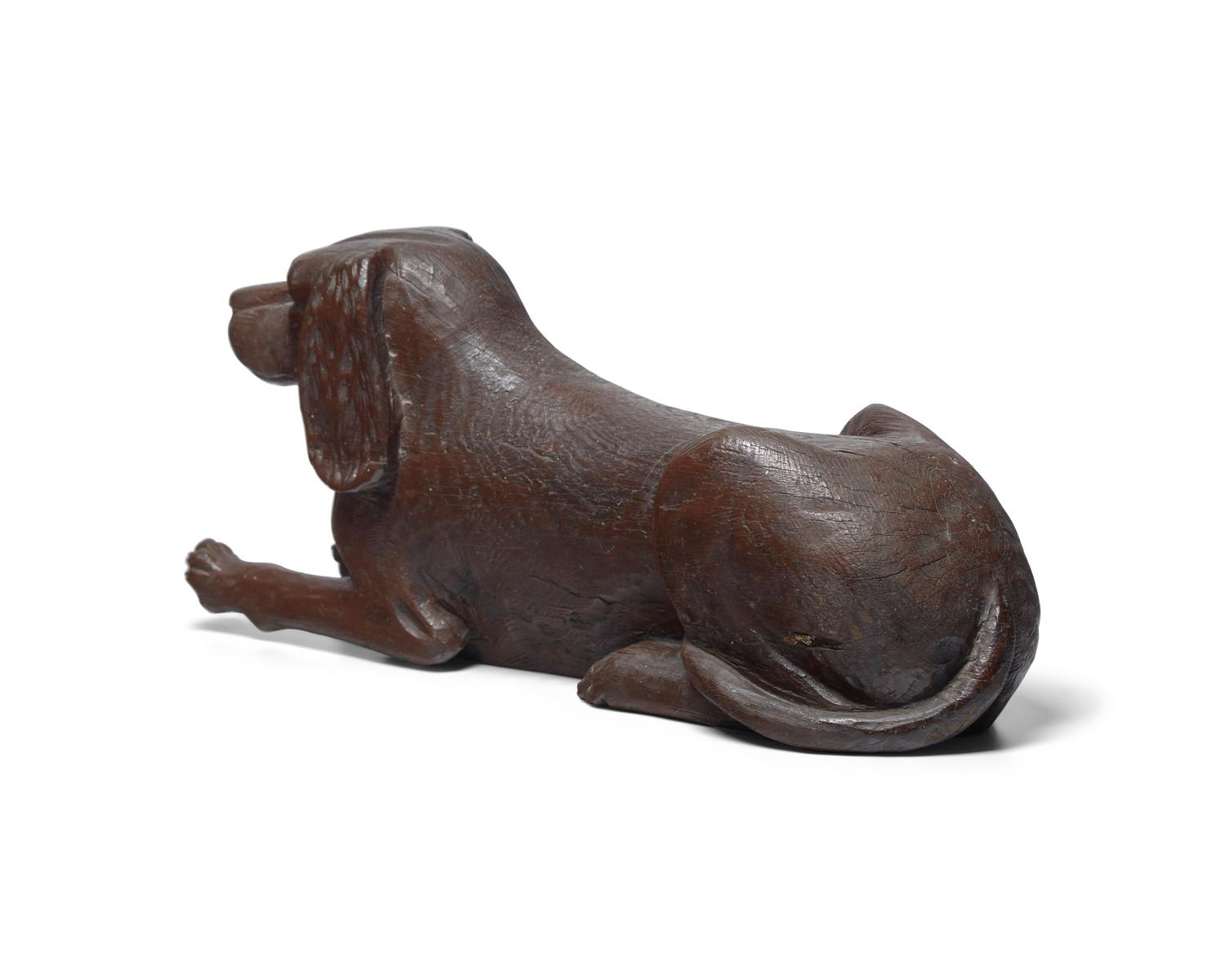 A Carved and Brown- Painted Figure of a Reclining Spaniel