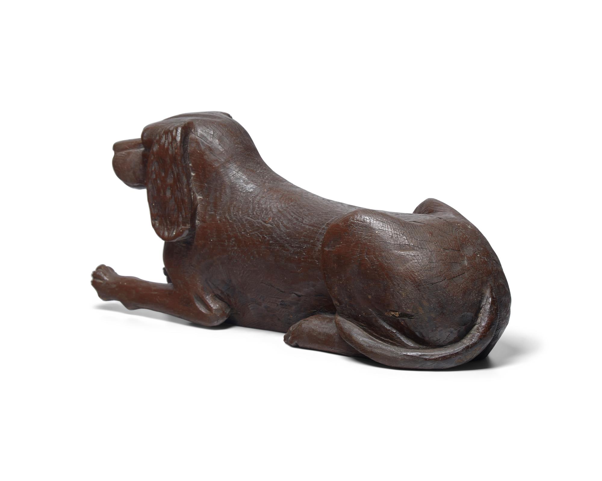 A Carved and Brown- Painted Figure of a Reclining Spaniel