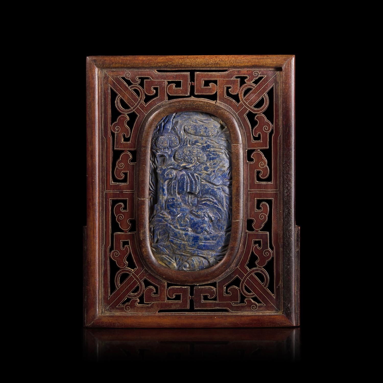 A Chinese Carved Lapis Lazuli Oval "Deer and Pine" Panel, Qing Dynasty — 清 硬木嵌青金石“鹿鶴同春”圖牌