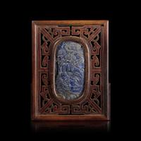 A Chinese Carved Lapis Lazuli Oval "Deer and Pine" Panel, Qing Dynasty — 清 硬木嵌青金石“鹿鶴同春”圖牌