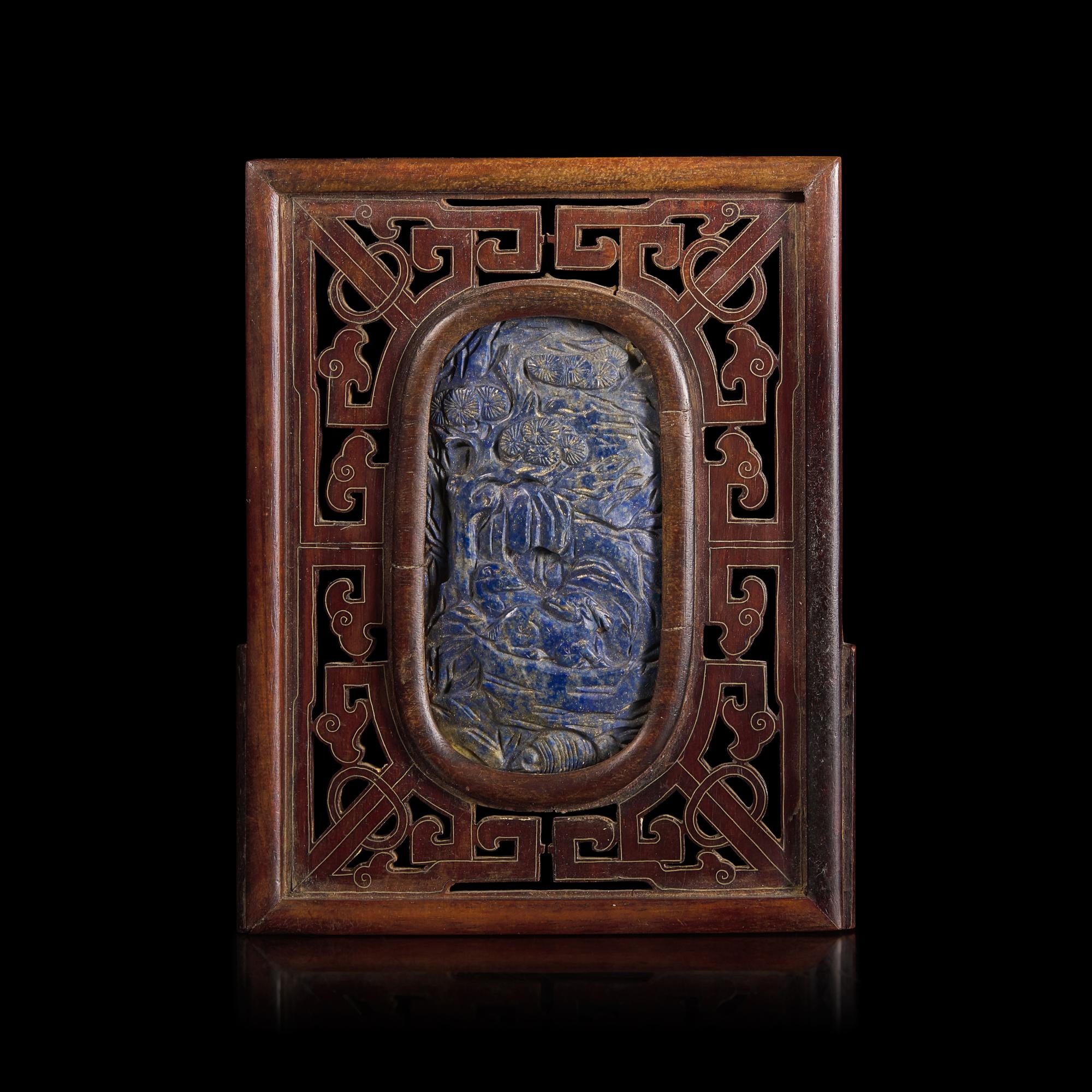 A Chinese Carved Lapis Lazuli Oval "Deer and Pine" Panel, Qing Dynasty — 清 硬木嵌青金石“鹿鶴同春”圖牌