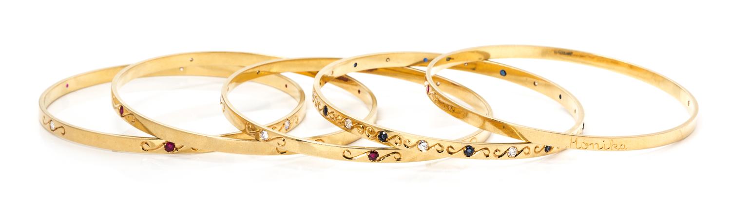 A Collection of 18 Karat Yellow Gold, Diamond, Ruby and Sapphire Bangle Bracelets, 61.80 dwts.