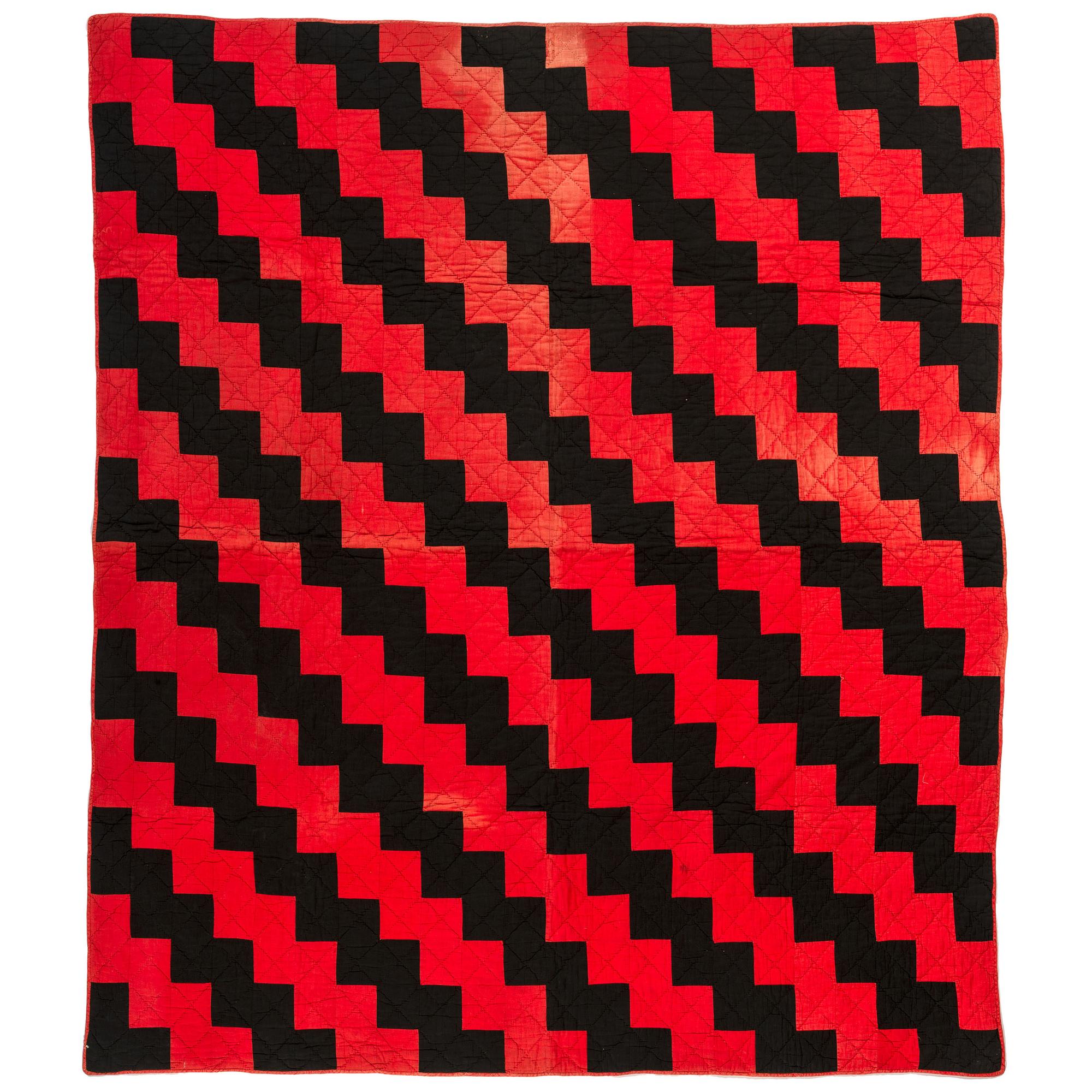 A Red and Black Pieced Zig Zag Pattern Quilt