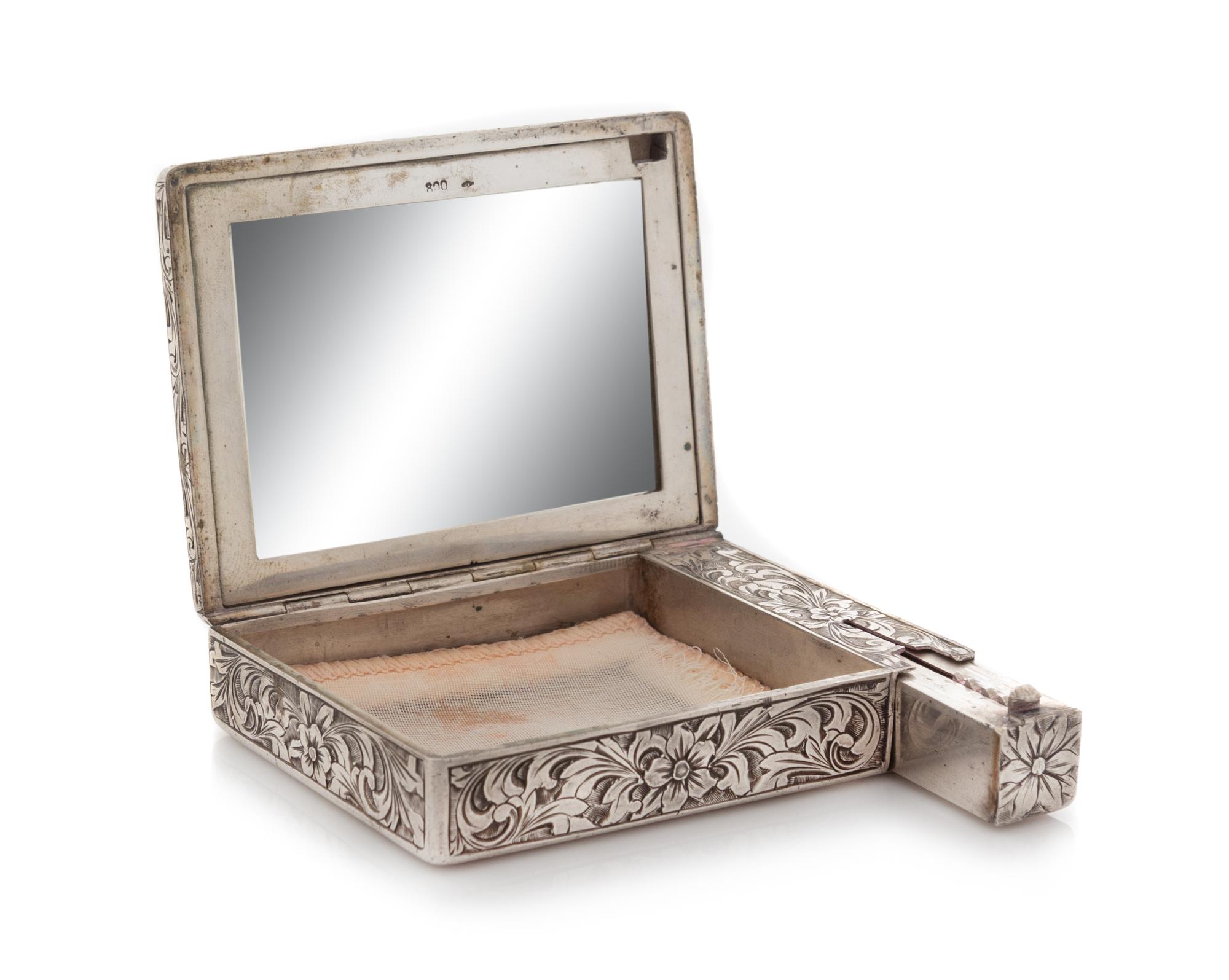 An Italian Silver Compact, First Half 20th Century, the case worked to show floral and foliate scroll decoration, opening to a mirrored