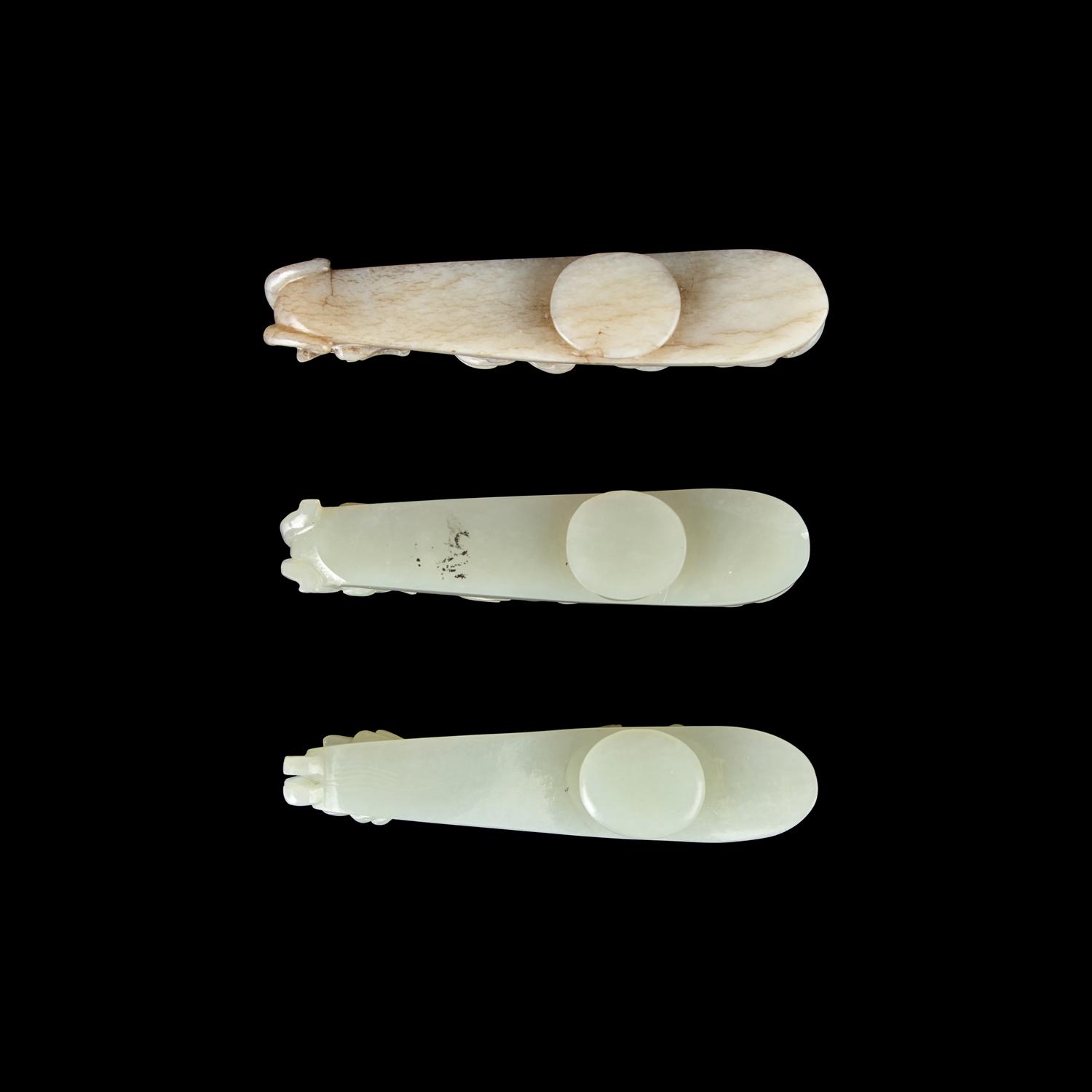 A Chinese 'Chicken-Bone' Jade and Two Pale Celadon Jade 'Dragon' Belt Hooks, Qing Dynasty 清 玉龍鉤三件
