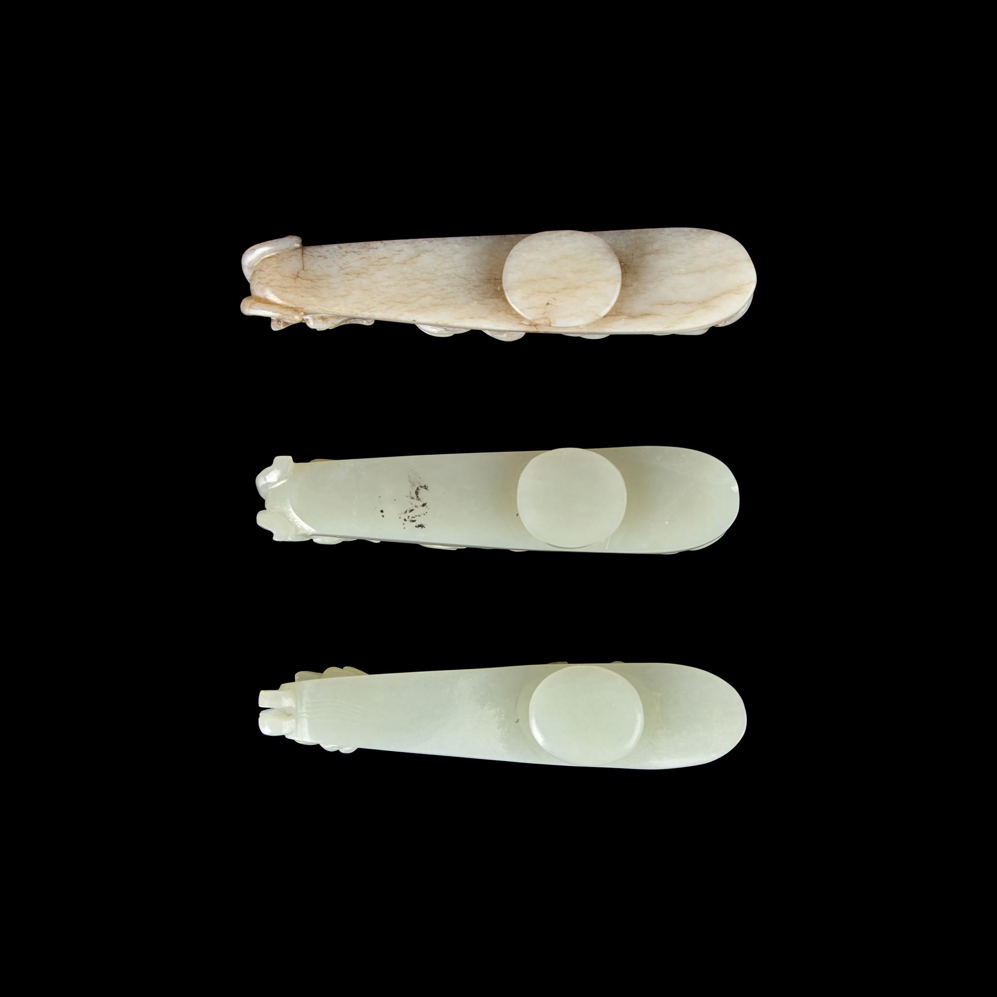 A Chinese 'Chicken-Bone' Jade and Two Pale Celadon Jade 'Dragon' Belt Hooks, Qing Dynasty 清 玉龍鉤三件