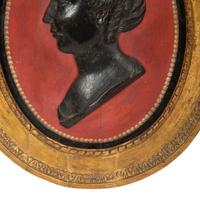A Pair of Giltwood Framed Ebonized Relief Portrait Plaques of French Nobility, 18th Century