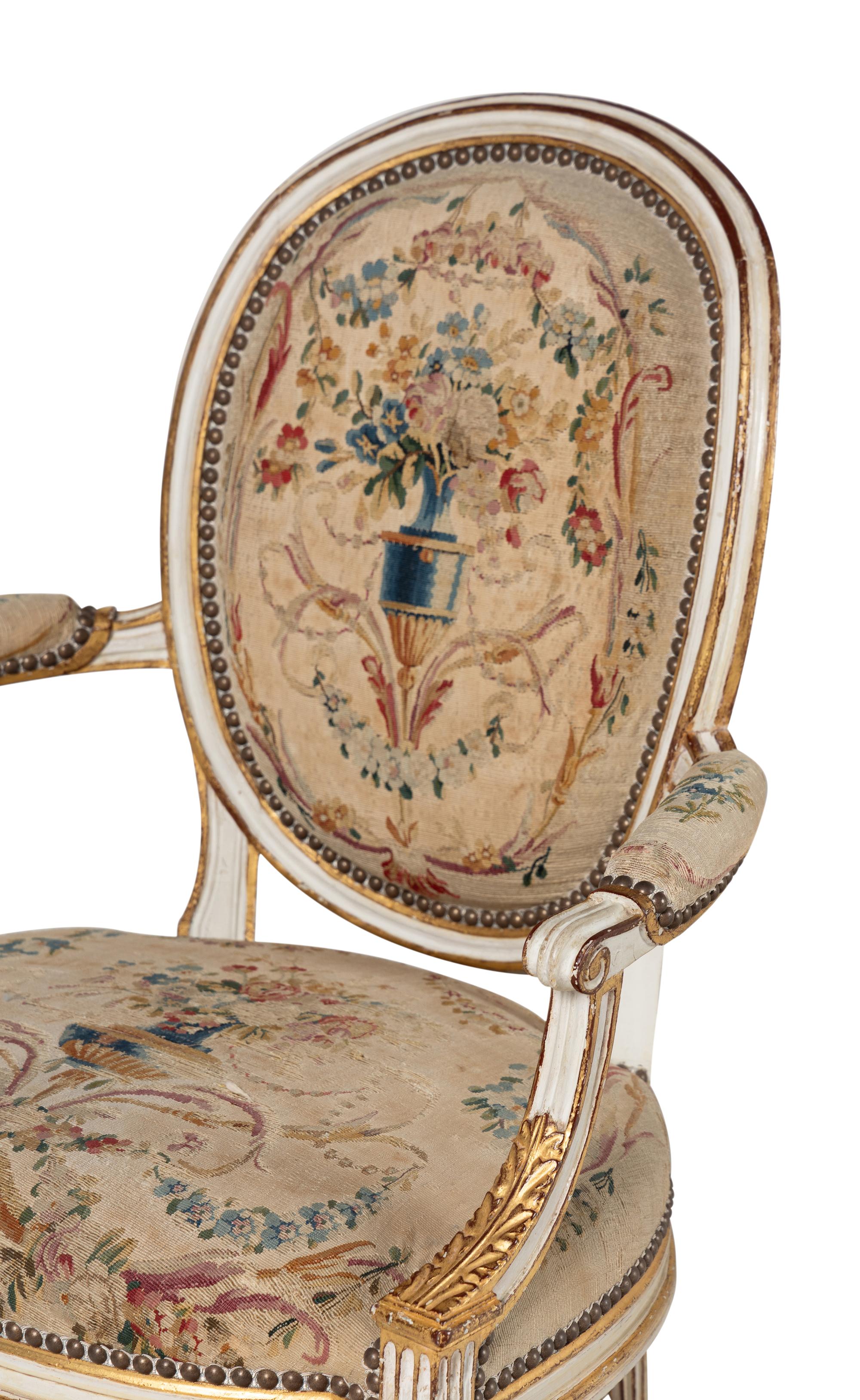 A Set of Four Louis XVI Crème-Painted and Parcel Gilt Fauteuils