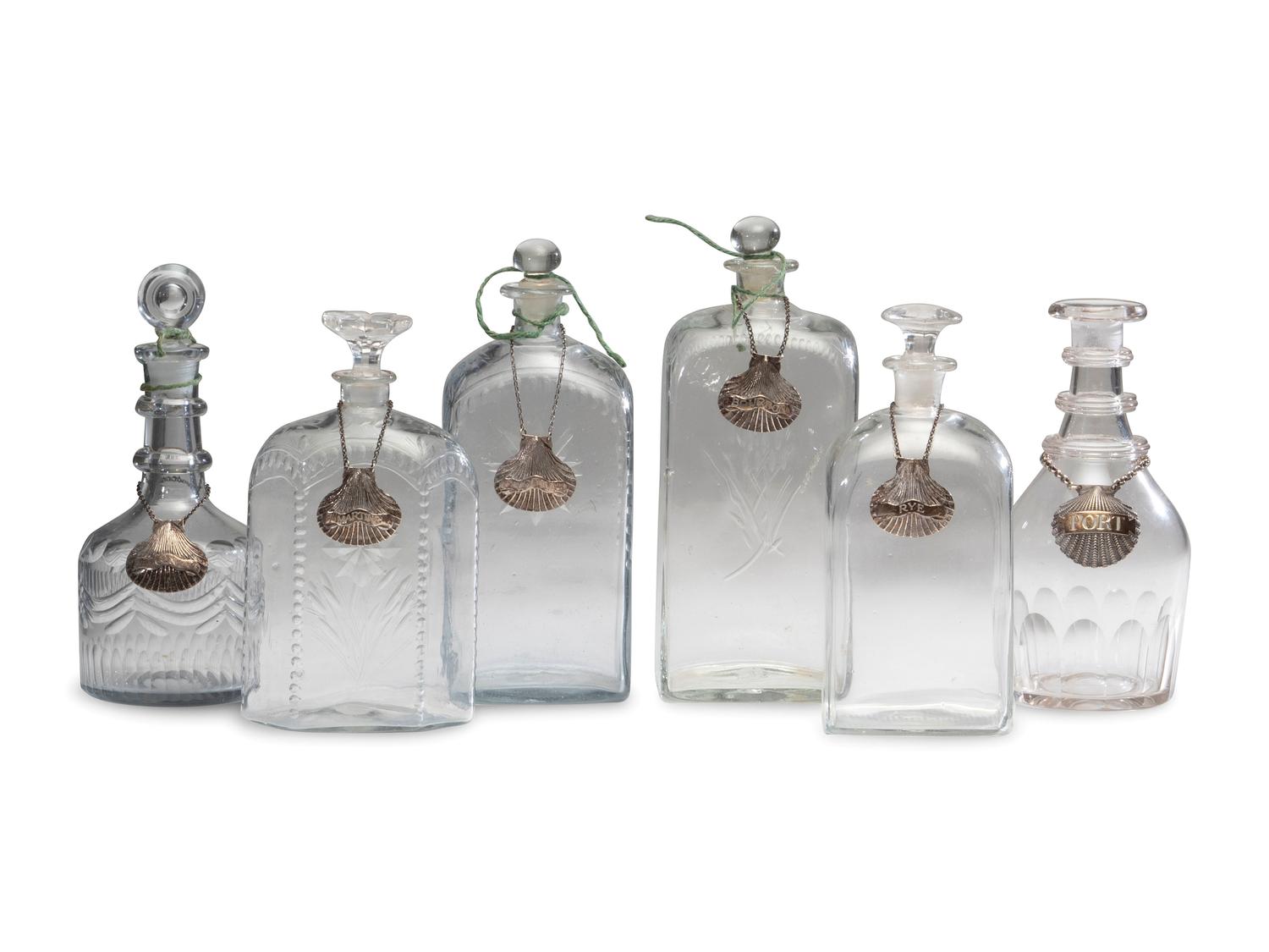 Fifteen Glass Decanters with English Shell-Form Silver Bottle Tags