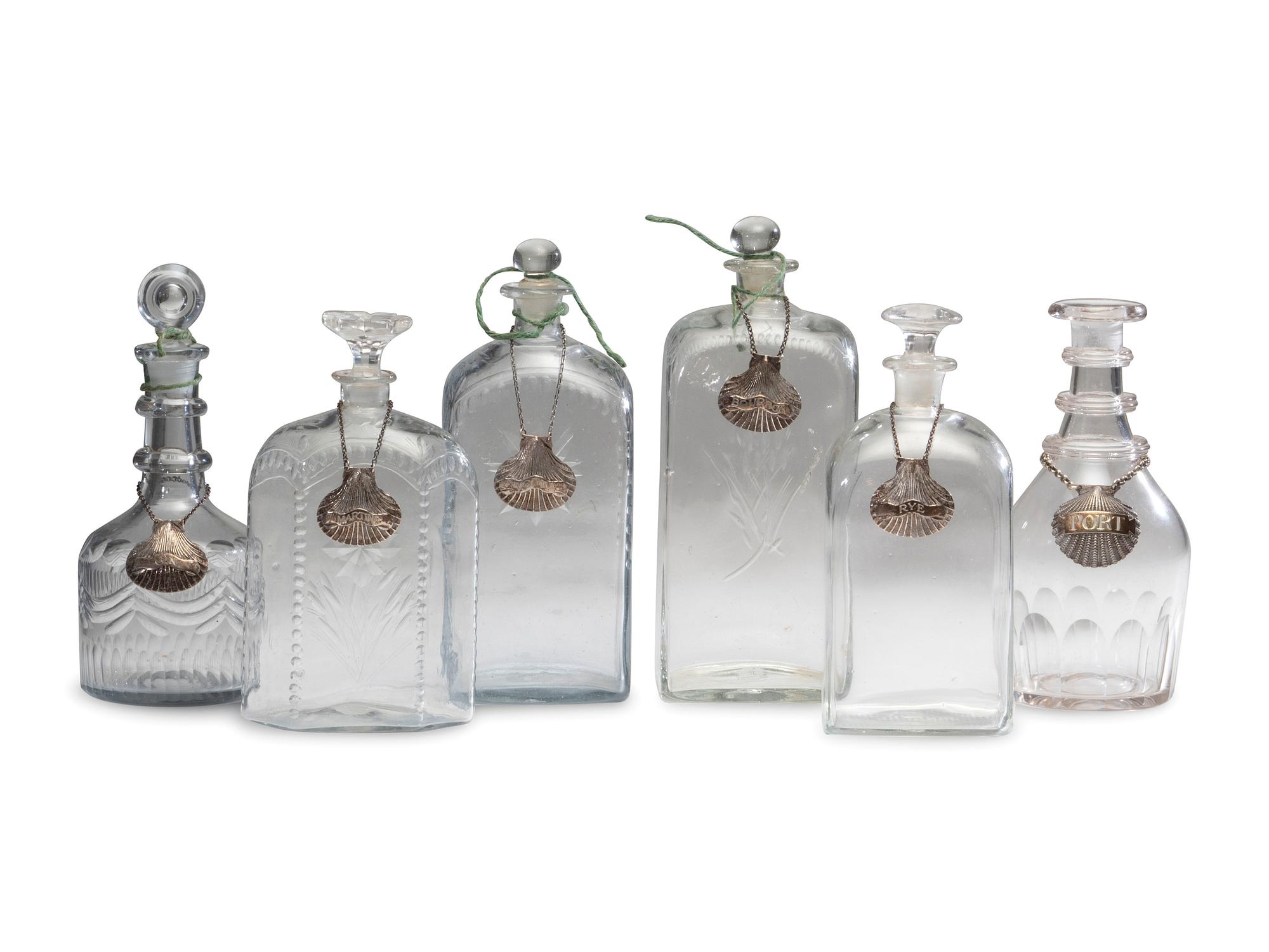 Fifteen Glass Decanters with English Shell-Form Silver Bottle Tags