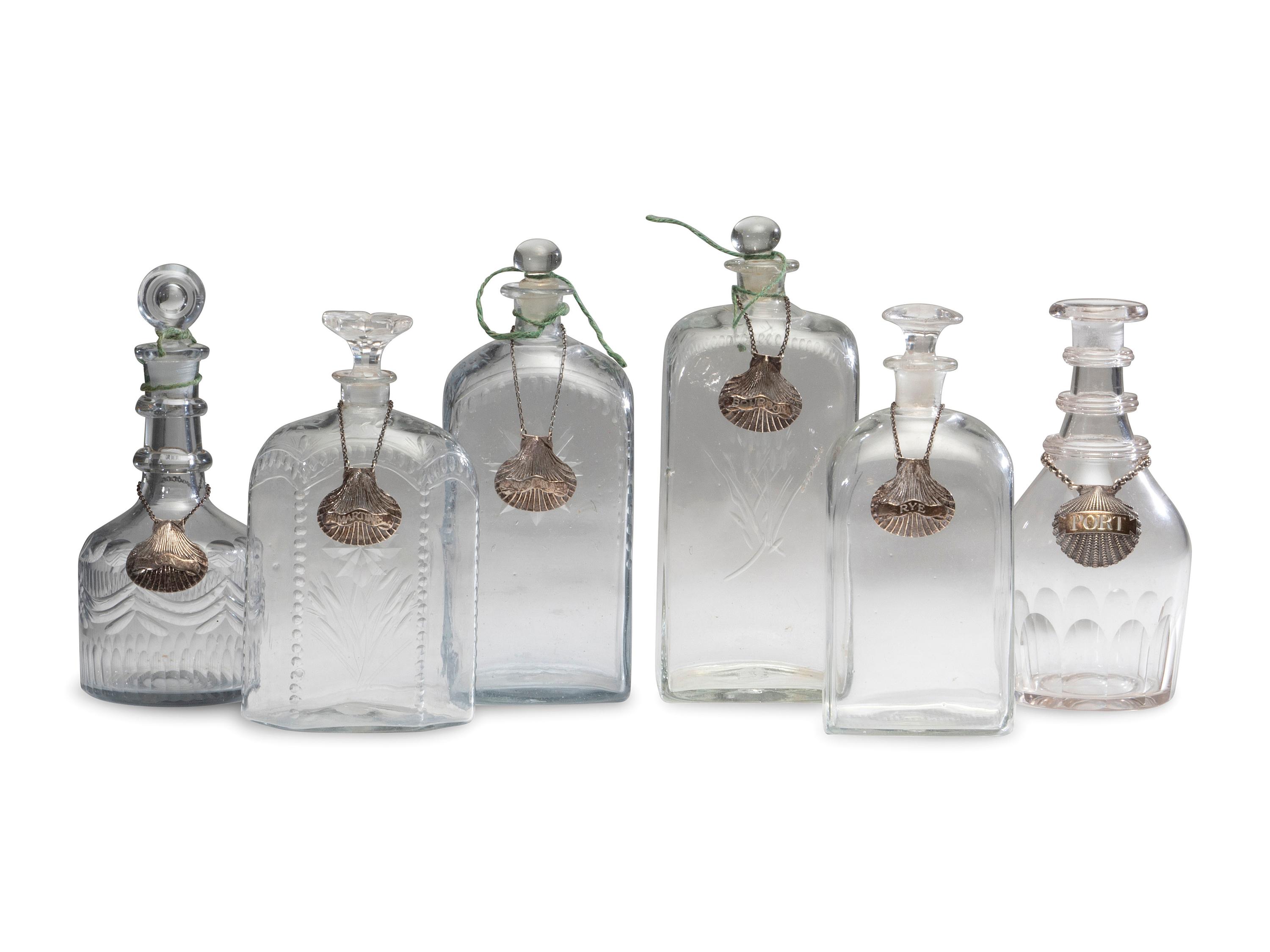 Fifteen Glass Decanters with English Shell-Form Silver Bottle Tags