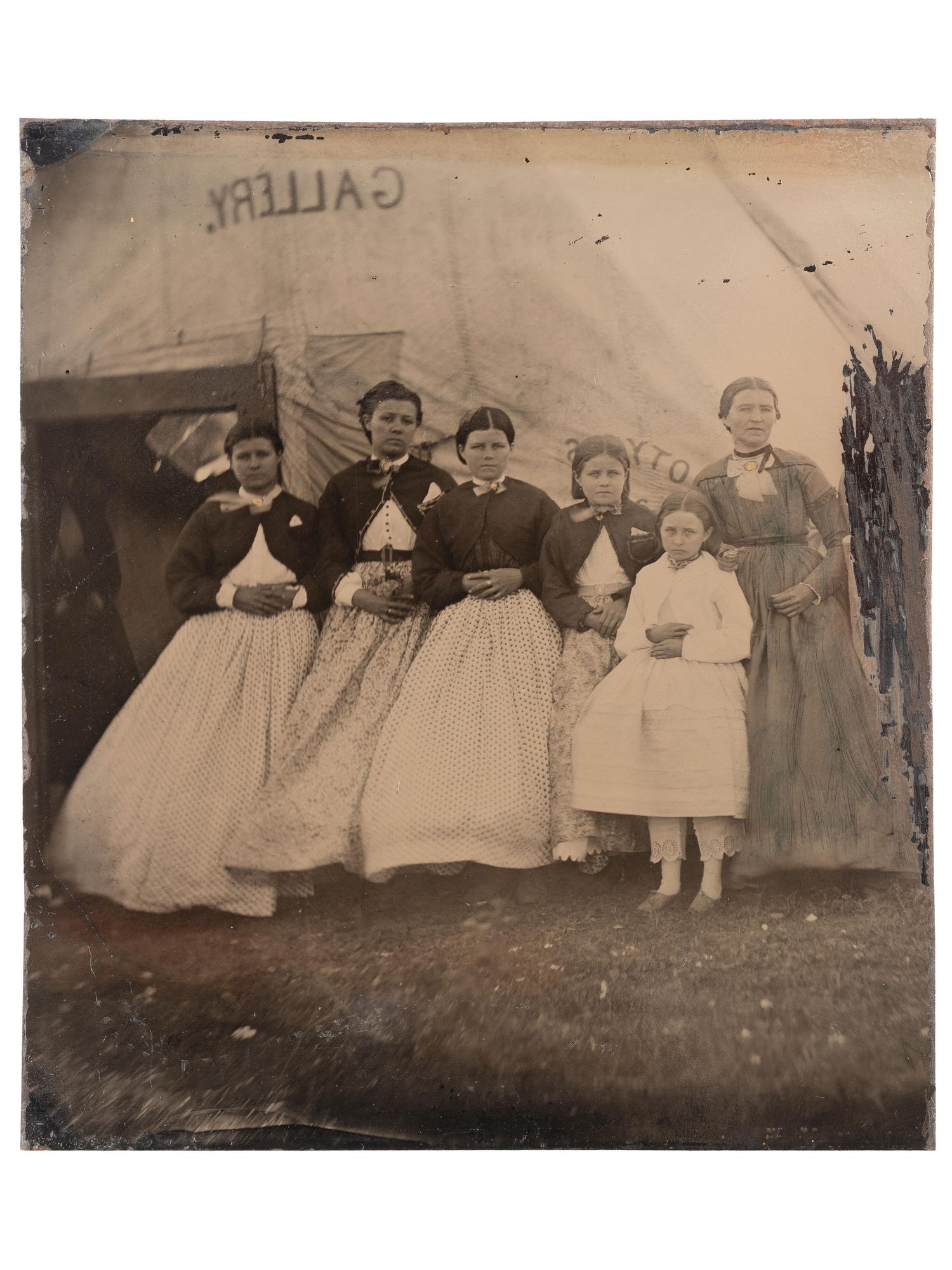 [EARLY PHOTOGRAPHY]. Tintype featuring a group of women standing outside of a Civil War photographer's tent, possibly at Camp Parole, Annapolis, MD.