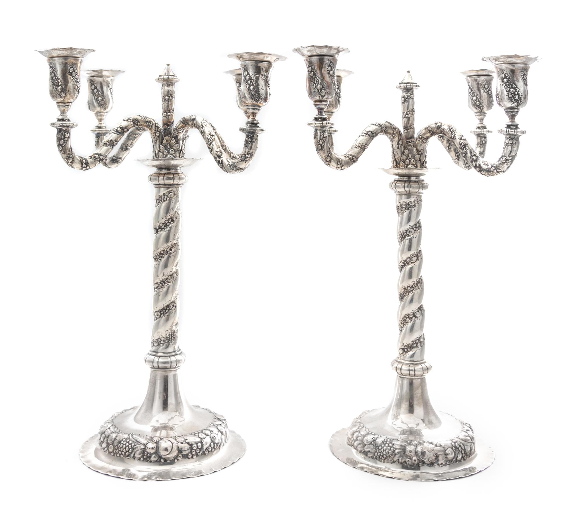 A Pair of German Silver Four-Light Candelabra, Early 20th Century, each central stem issuing four S-scroll candle arms worked to show t