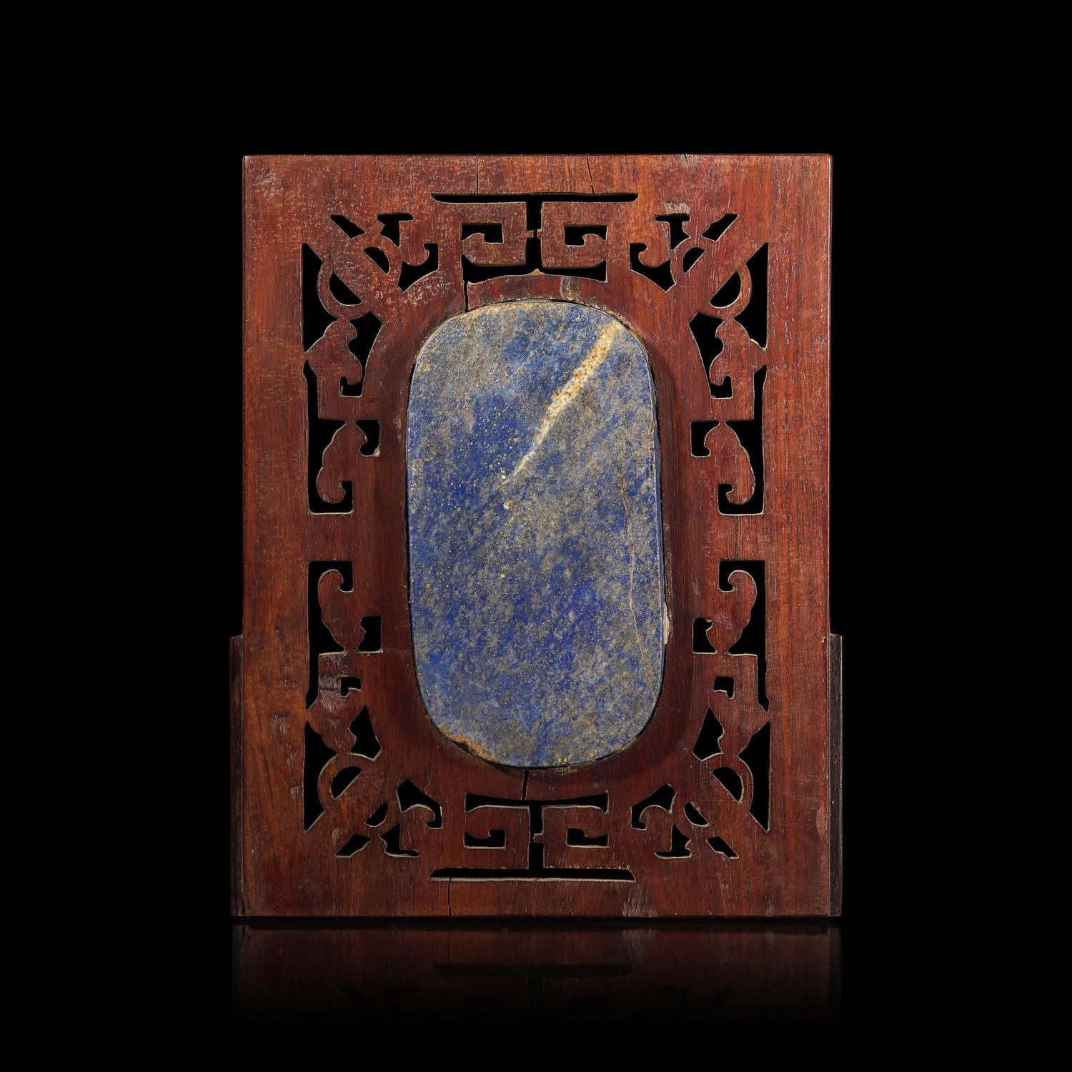 A Chinese Carved Lapis Lazuli Oval "Deer and Pine" Panel, Qing Dynasty — 清 硬木嵌青金石“鹿鶴同春”圖牌
