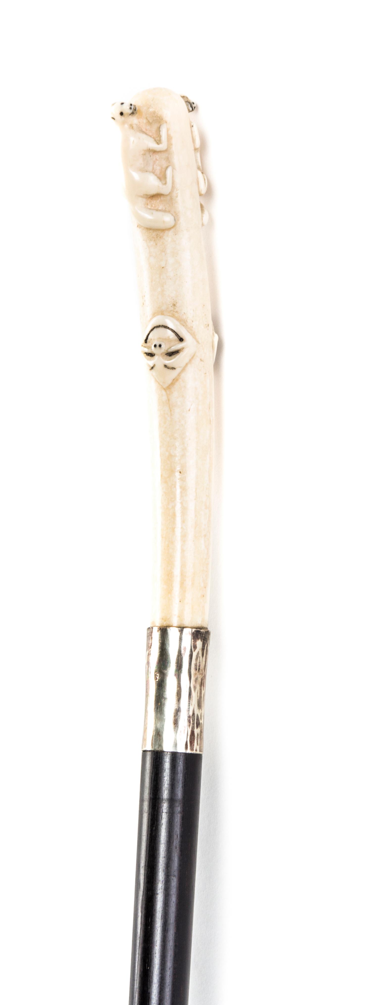 An American Inuit Carved Walrus Ivory Handled Walking Stick, Length of handle 5 3/4 x length overall 34 1/2 inches.