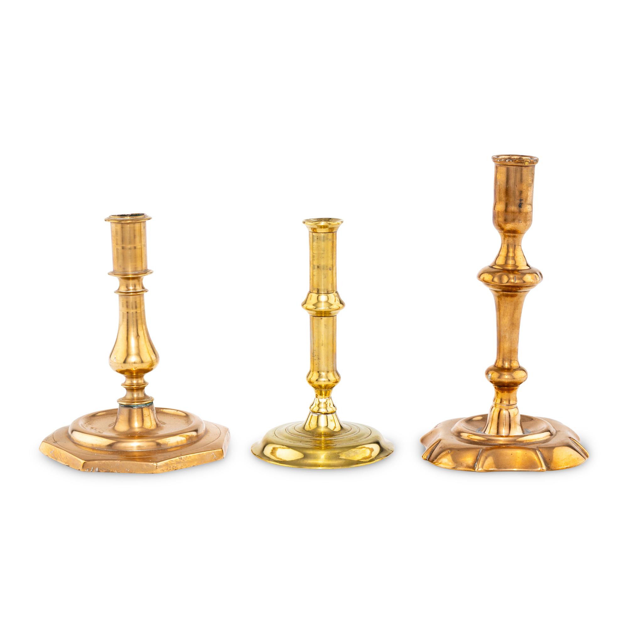 A Collection of Three Brass and Bell Metal Candlesticks