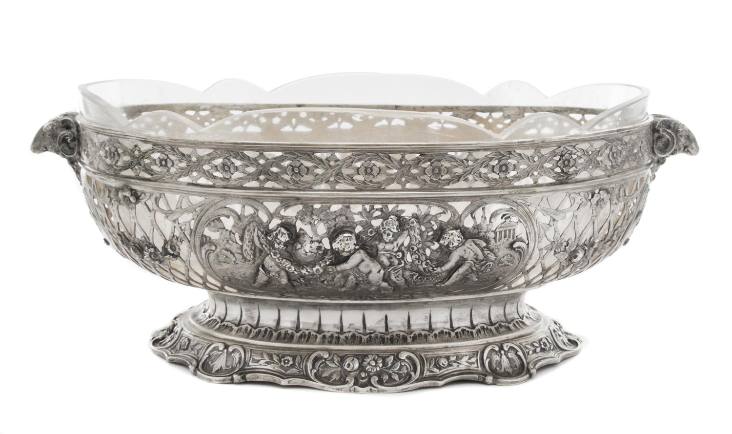 A German Silver Center Bowl, , having pierced floral and C-scroll decoration interspersed with two cartouches depicting putti in a gard