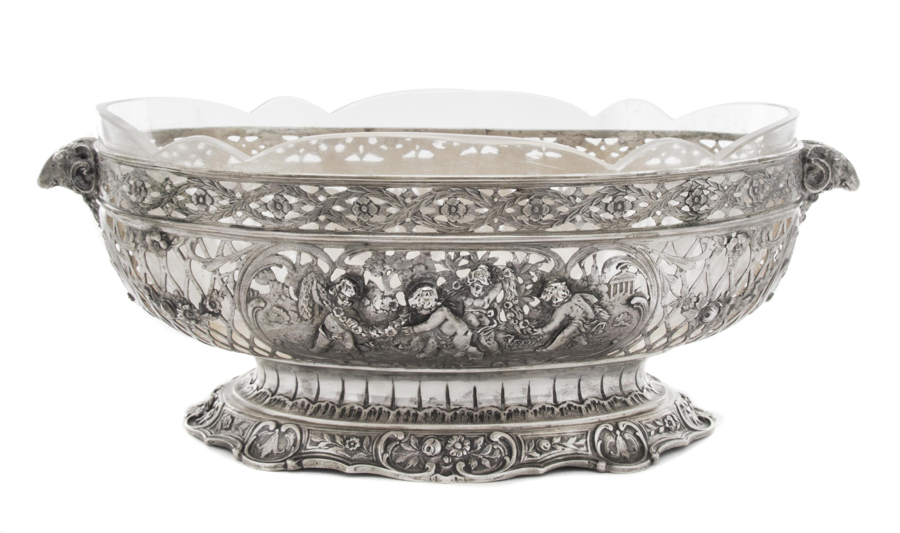A German Silver Center Bowl, , having pierced floral and C-scroll decoration interspersed with two cartouches depicting putti in a gard