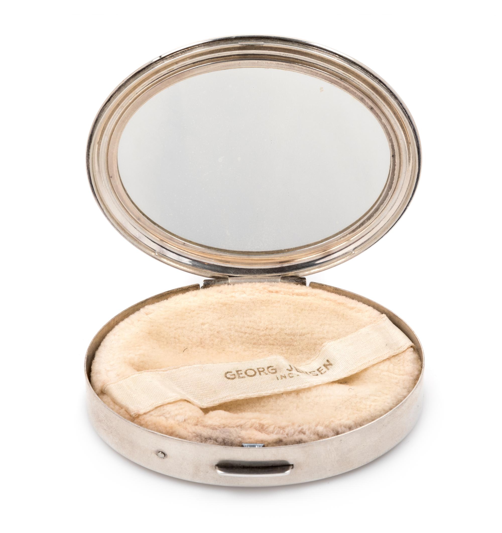 An American Silver Compact, Georg Jensen Inc., New York, NY, Circa 1940, or oval form, the lid with an engraved name and applied foliat