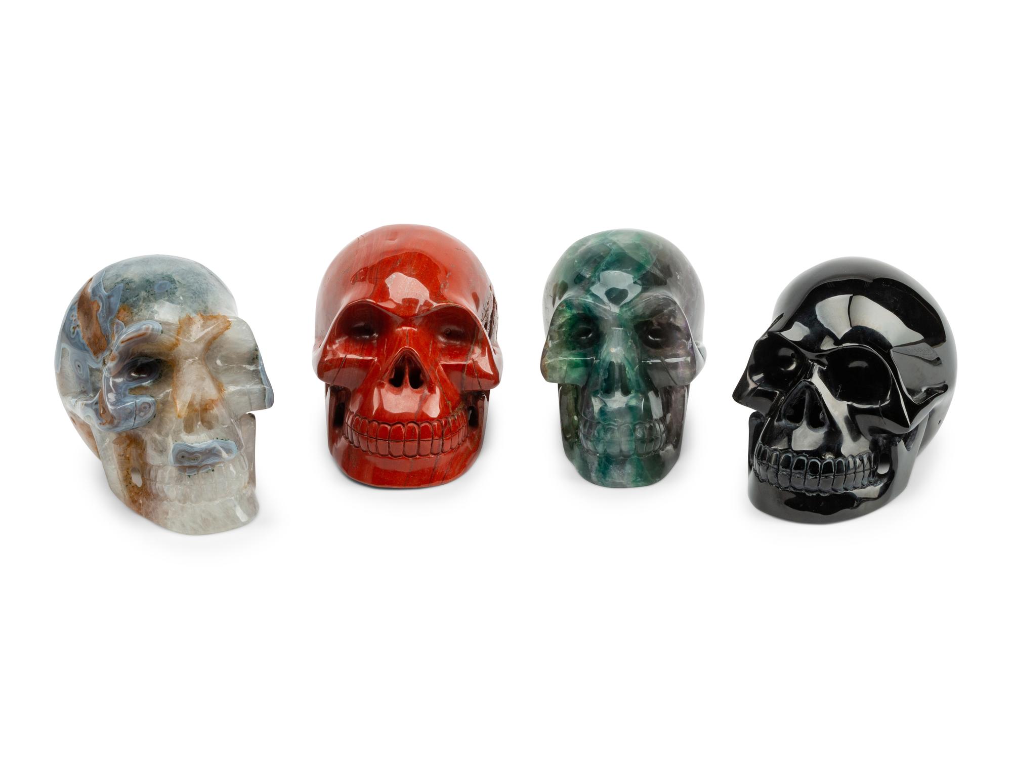 A Set of Four Carved Agate, Fluorite, Red Jasper and Black Obsidian Skulls