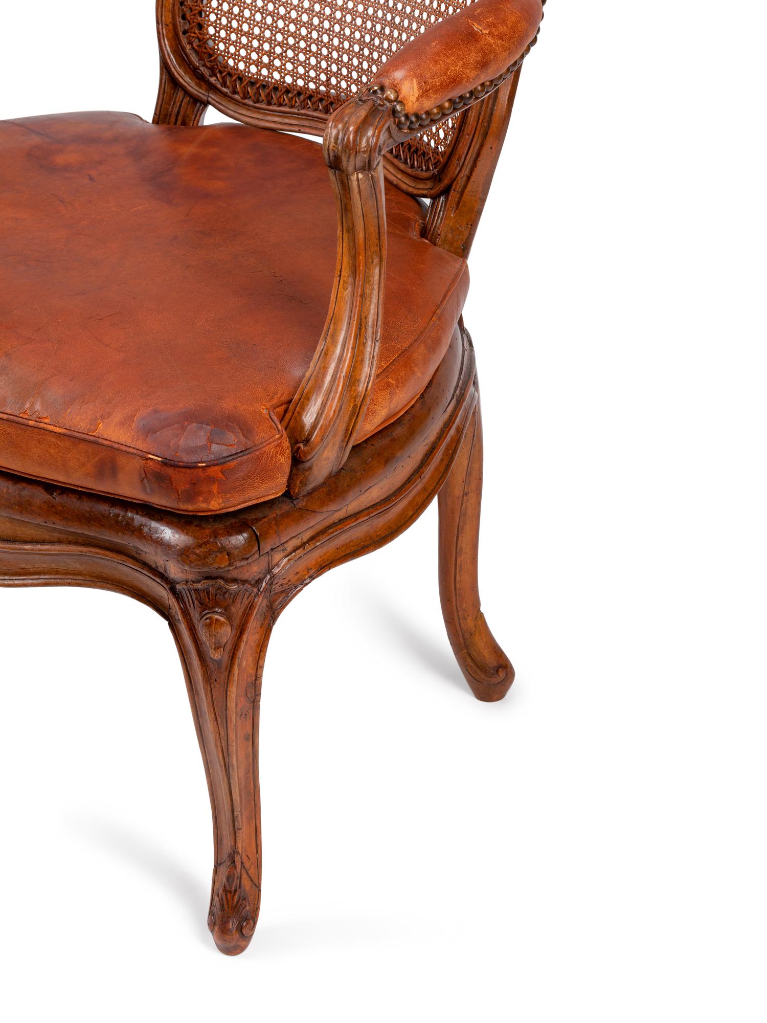 A Pair of Louis XV Beechwood Fauteuils with Cane and Leather Seat Cushions