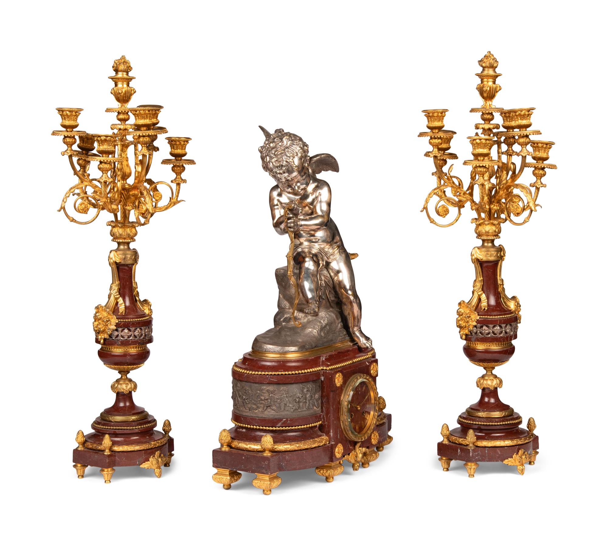 A French Gilt and Silvered Bronze and Rouge Marble Three-Piece Clock Garniture