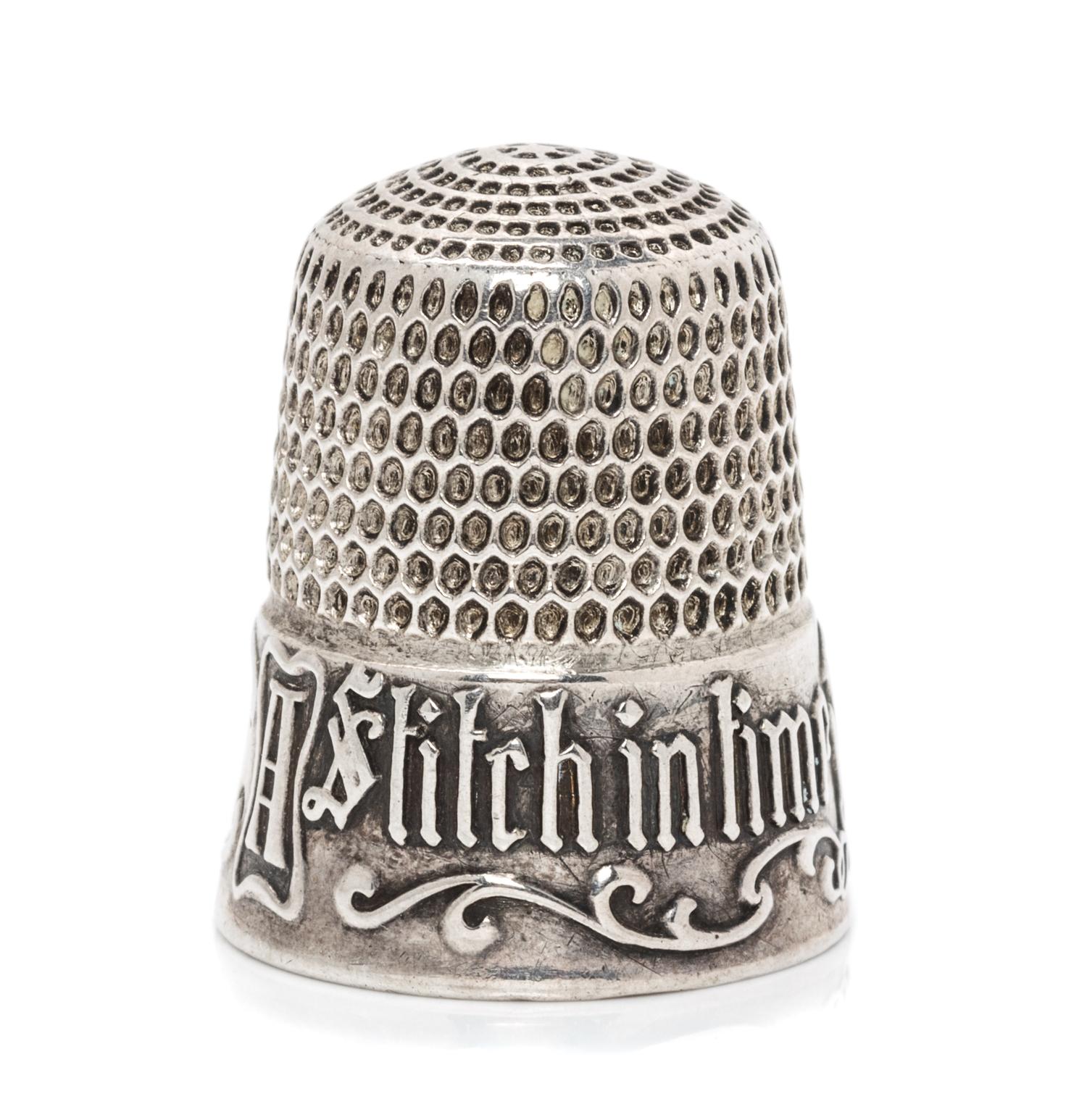 An American Silver Thimble, Simons Bros., Philadelphia, PA, the based marked A Stitch in Time Saves Nine with a vacant cartouche framed