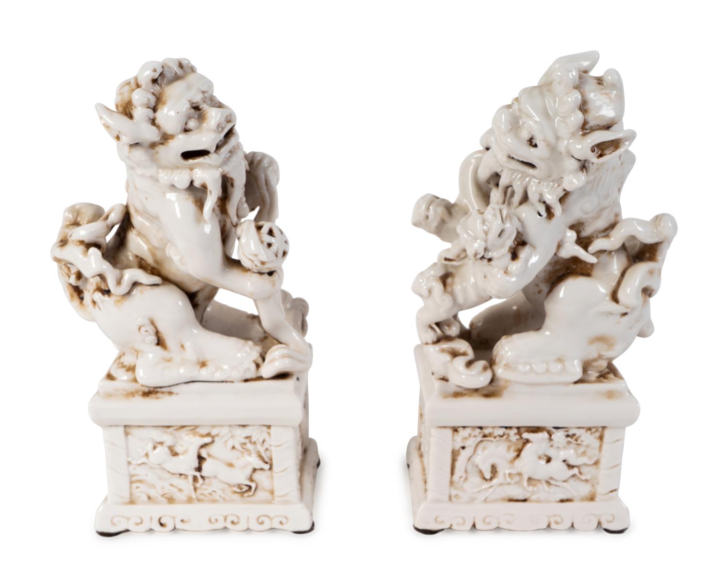 A Pair of Chinese Blanc de Chine Porcelain Fu-Lions on Pedestal Bases — 19TH/20TH CENTURY