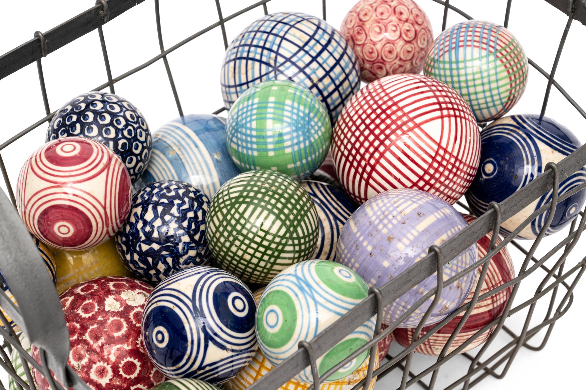 A Collection of English Polychrome Glazed Carpet Balls in a Wirework Basket