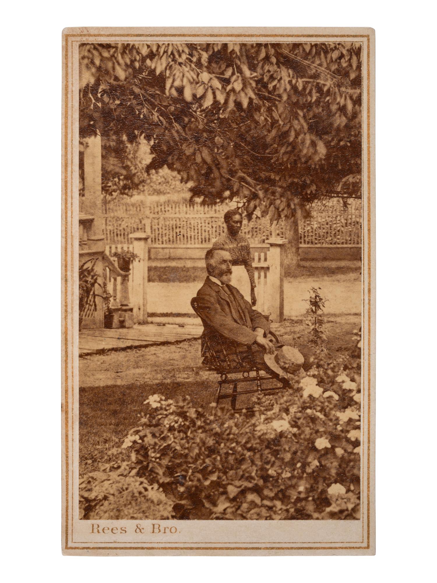 [AFRICAN AMERICANA]. Early post-bellum CDV of a female African American domestic worker standing in a garden behind a seated white gentleman. Richmond, VA: C. R. Rees & Bro, [1866].