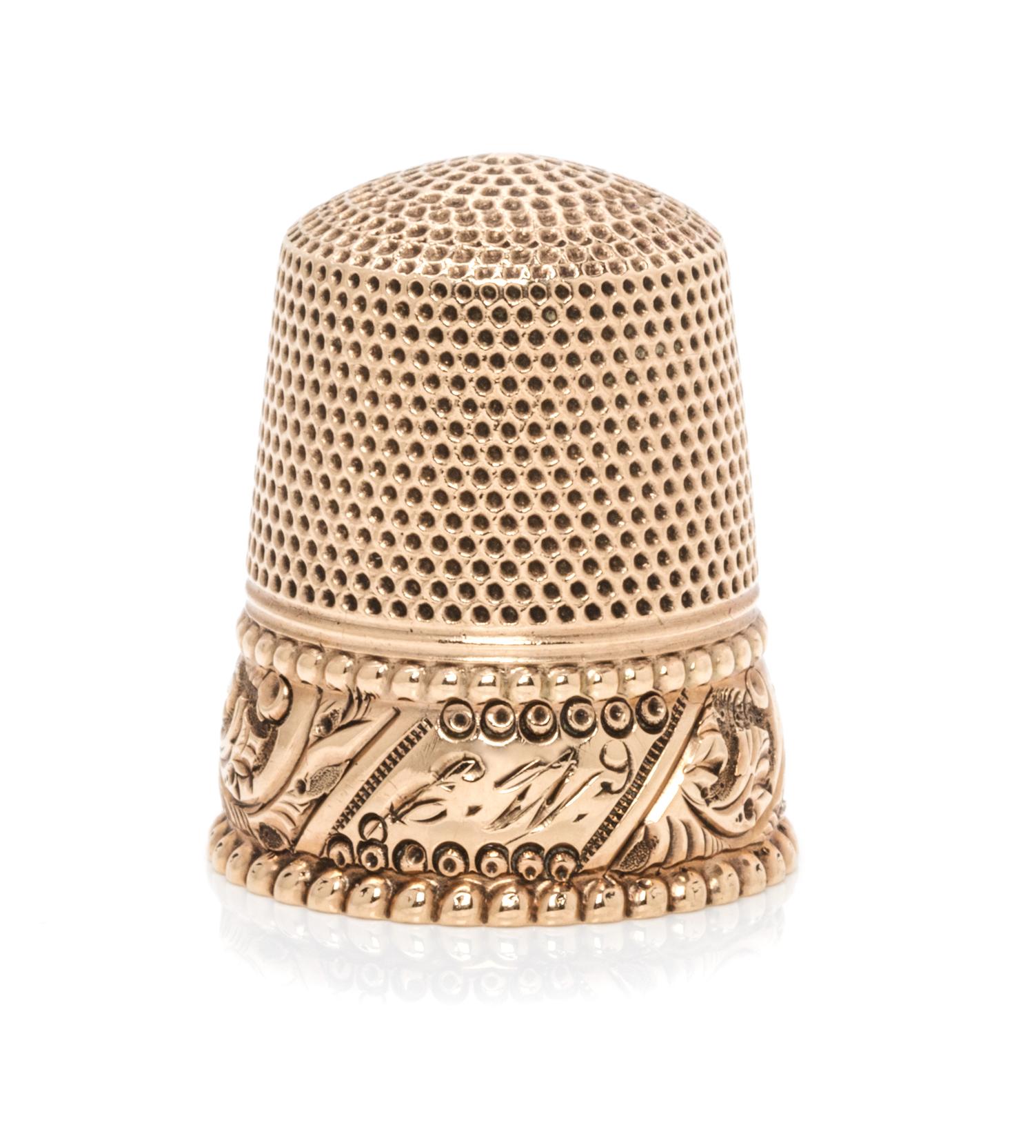 An American Yellow Gold Thimble, , having a knurled top and body above a foliate band with an engraved cartouche within two beaded band