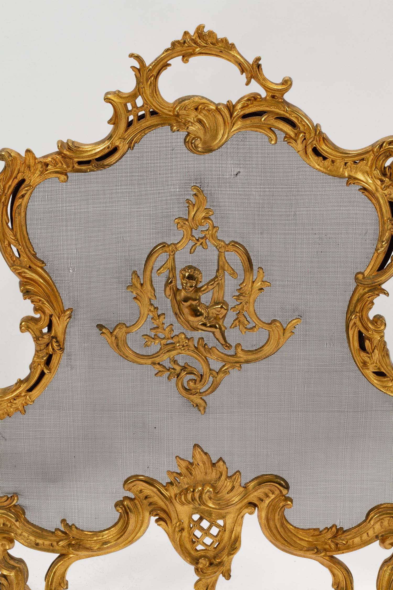 A Pair of Louis XV Style Gilt Bronze Chenets and a Similar Fire Screen