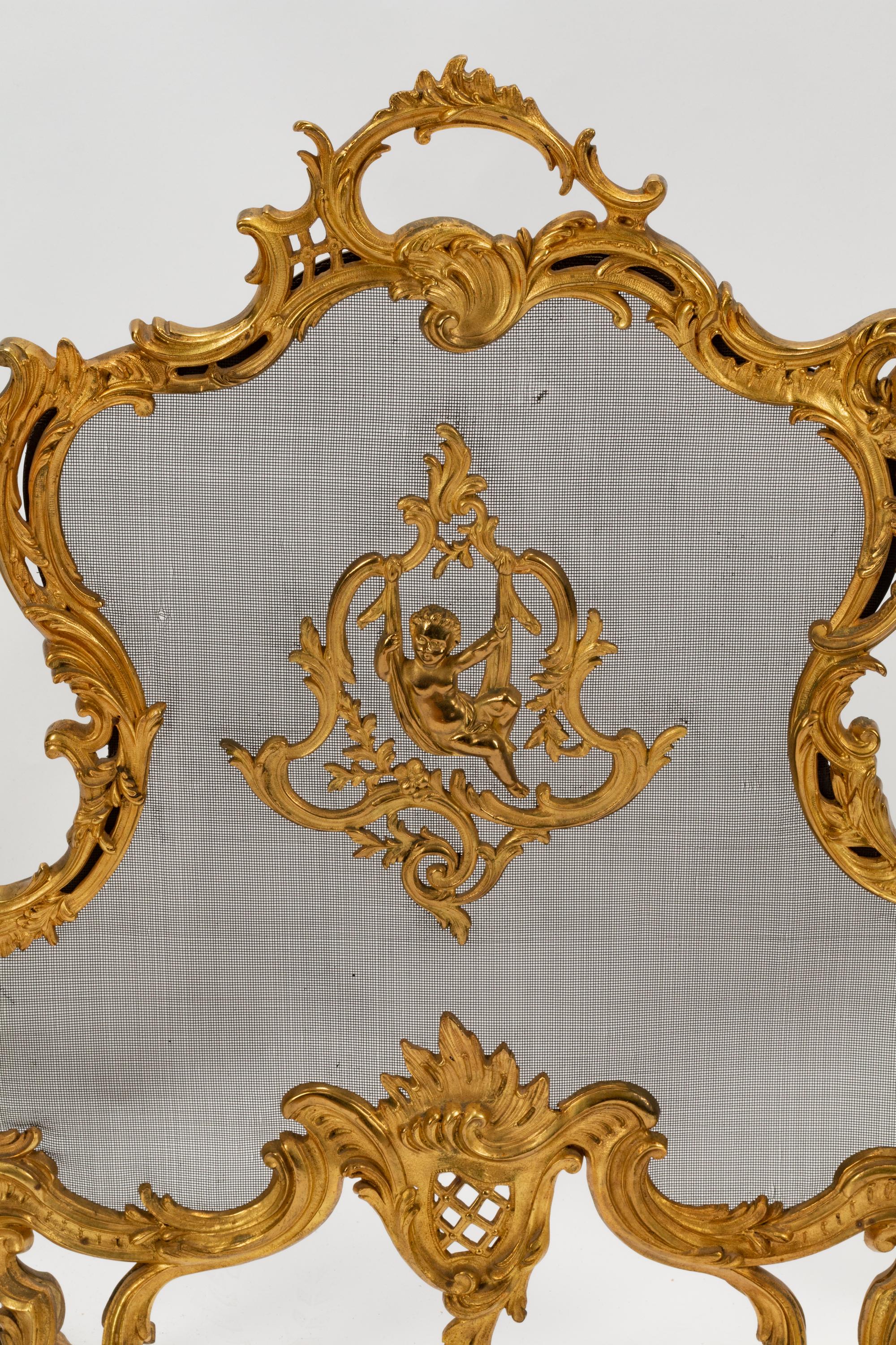 A Pair of Louis XV Style Gilt Bronze Chenets and a Similar Fire Screen