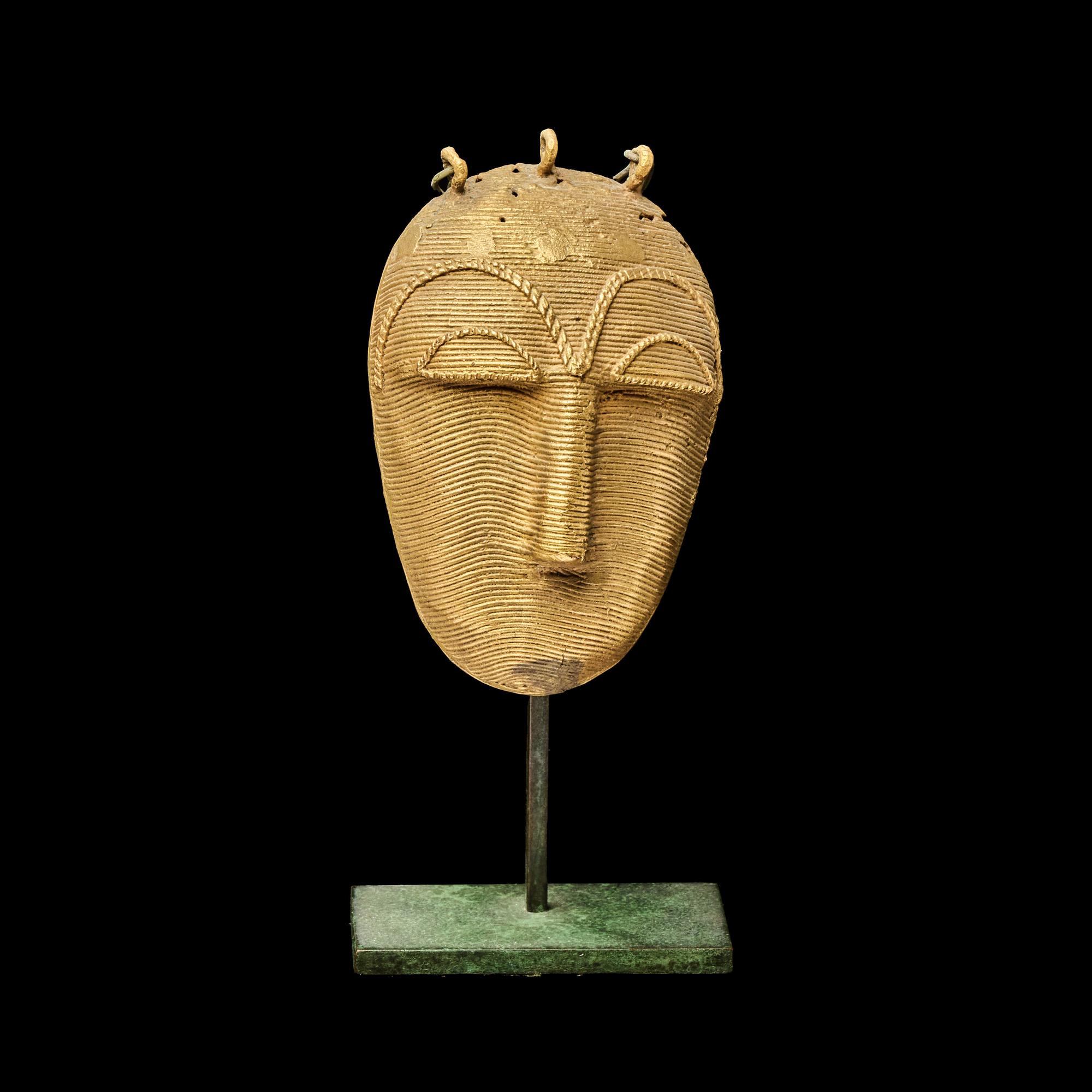 A Lagoons Region Gilt-Brass Mask Pendant