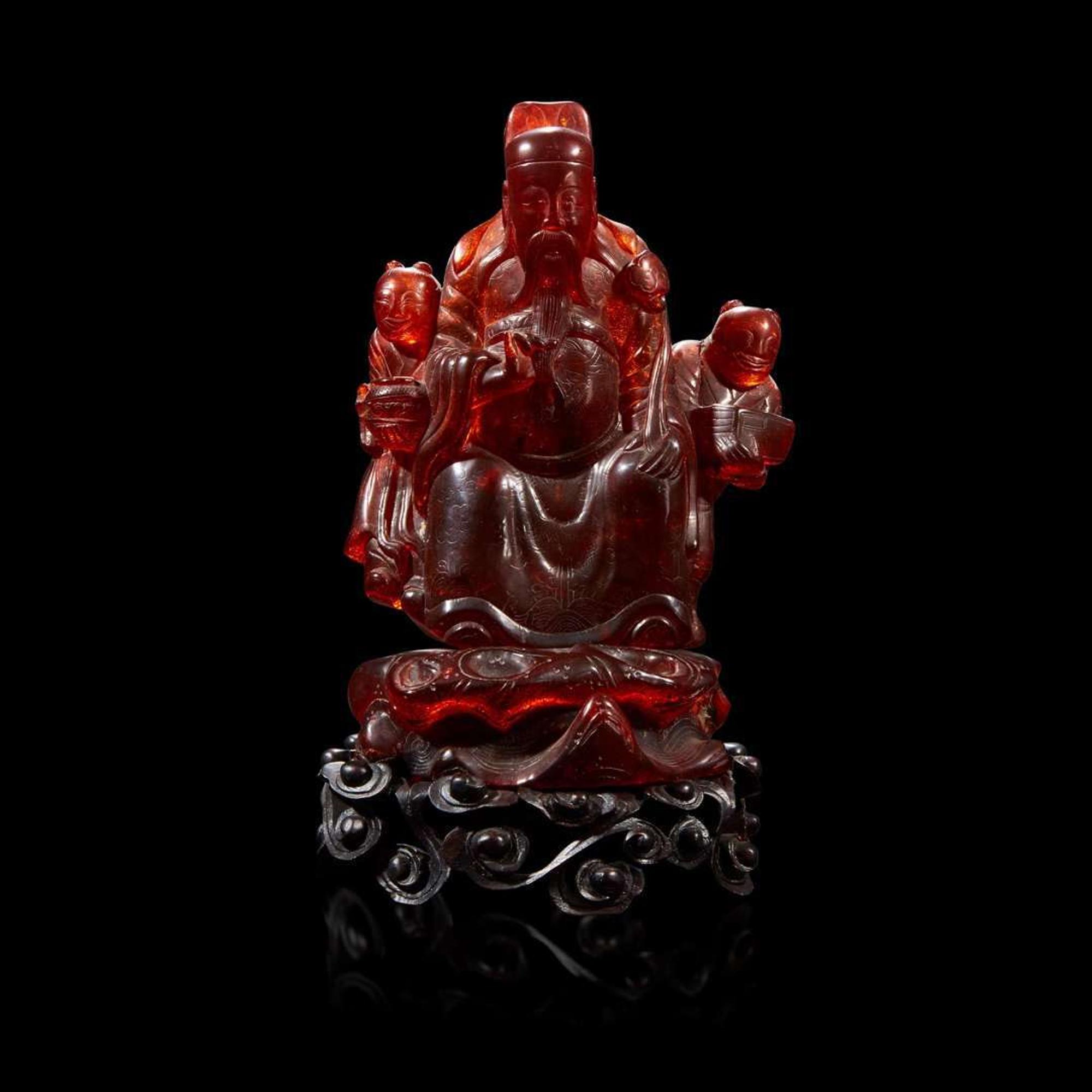 A Chinese carved amber figure of a sage and acolytes