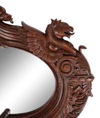A Carved Mahogany Oval Mirror with Opposing Griffins