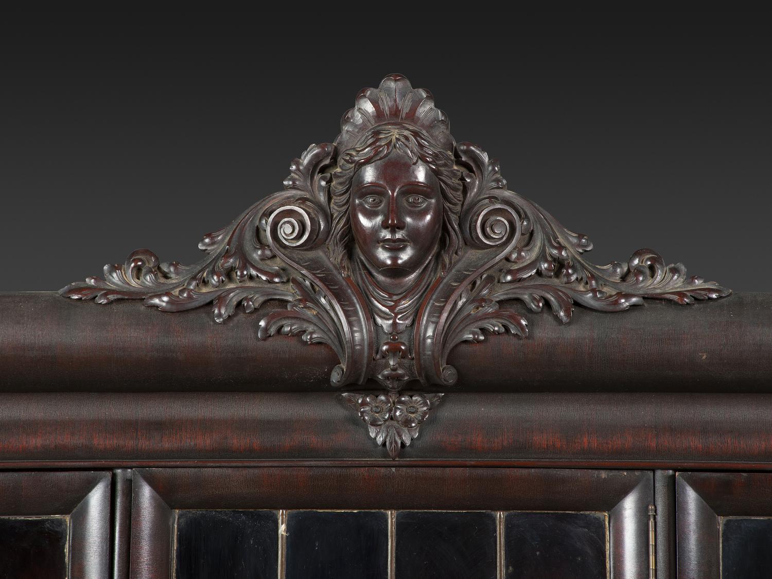 An Aesthetic Movement Crane and Mask Carved Mahogany and Glass Paneled Bookcase